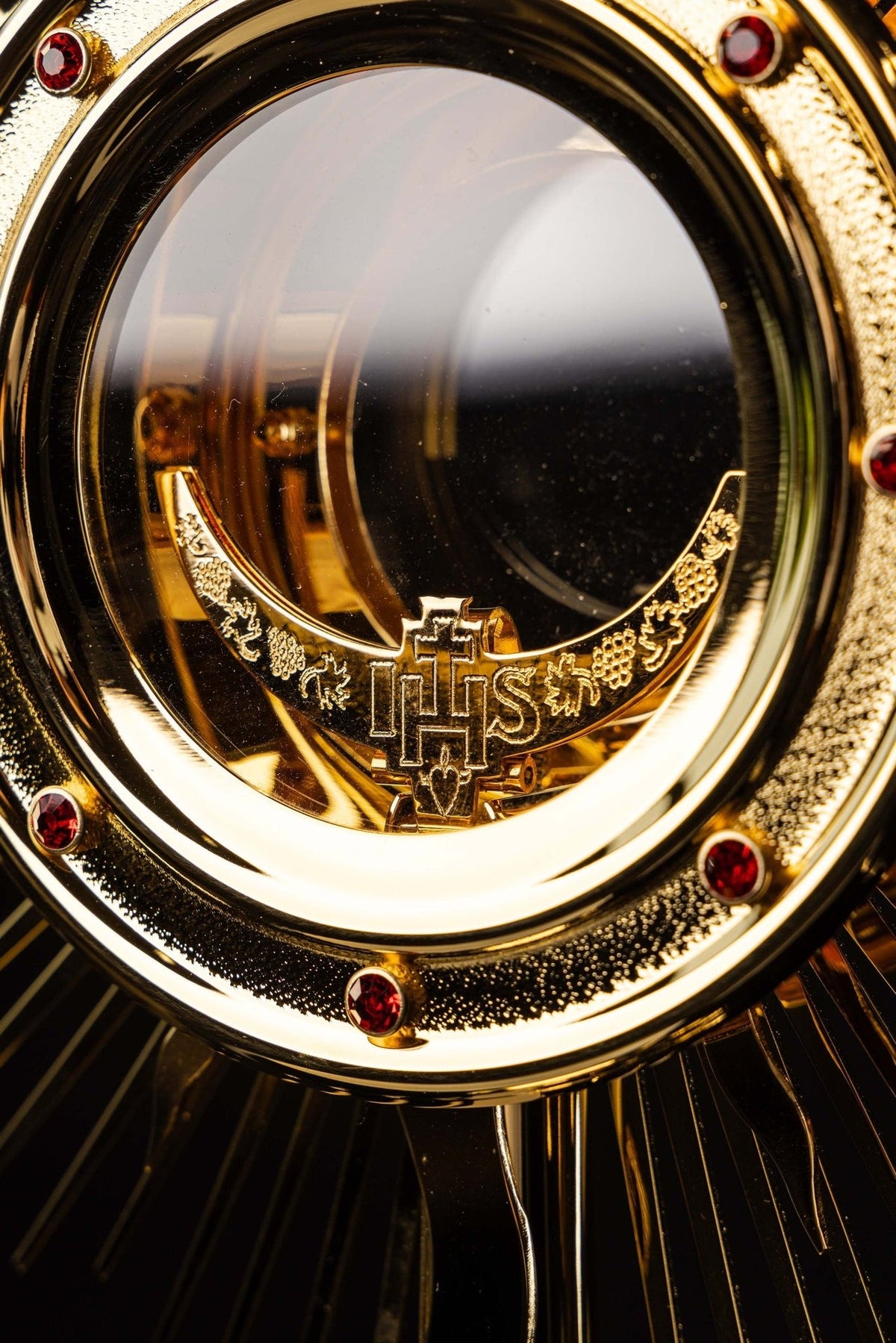 Gold-plated radiant monstrance close-up showing the glass luna and IHS detail