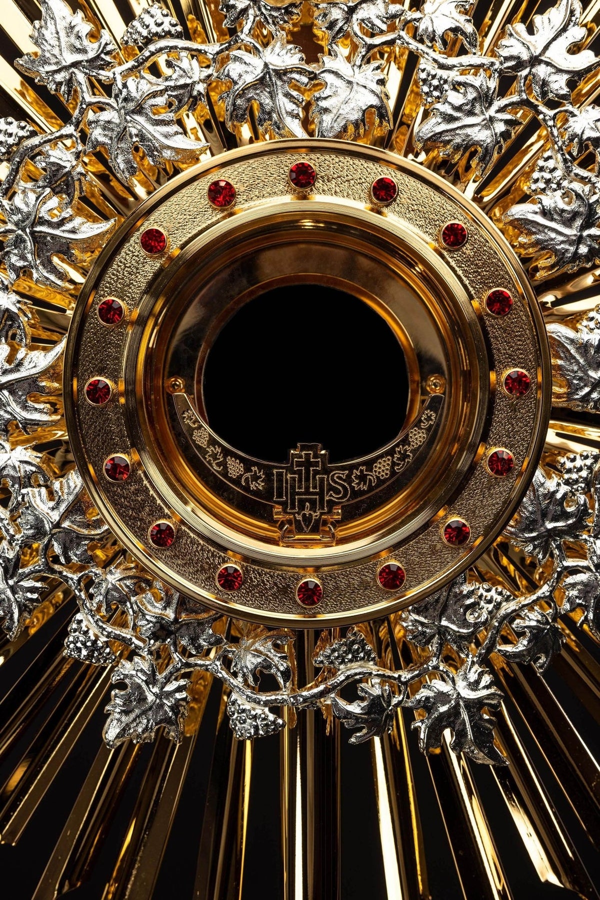 Monstrance close-up of gold-plated host holder with red rubies and IHS detail