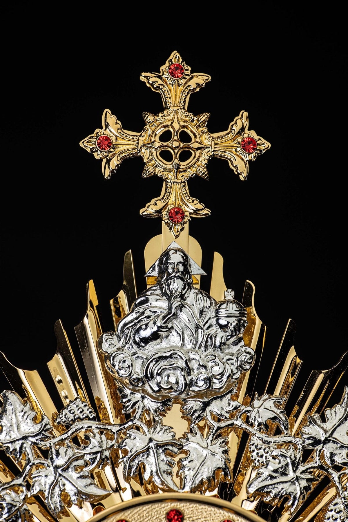 Monstrance close-up showing silver vine and grape motifs around the radiant center