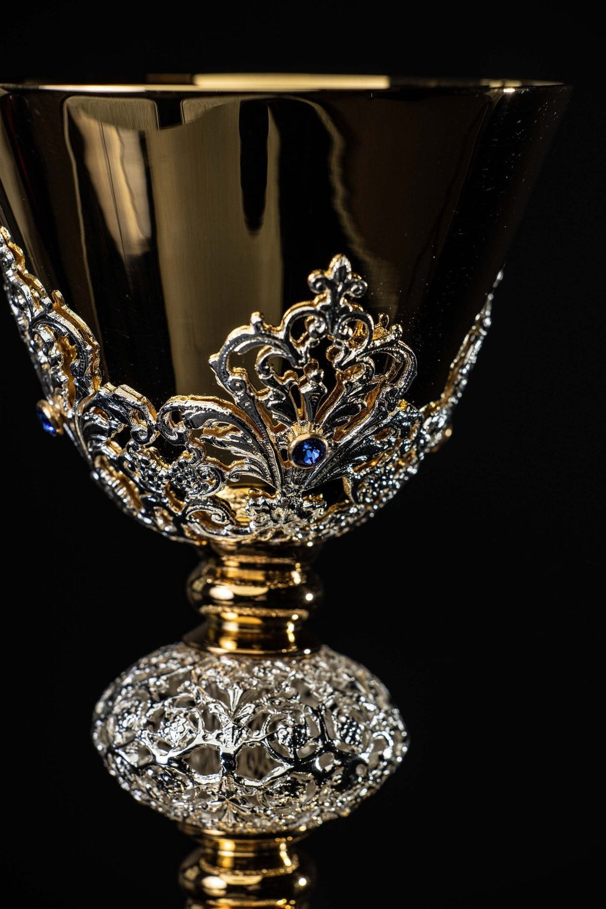 Gold-plated chalice close-up showing polished cup and ornate floral appliqué