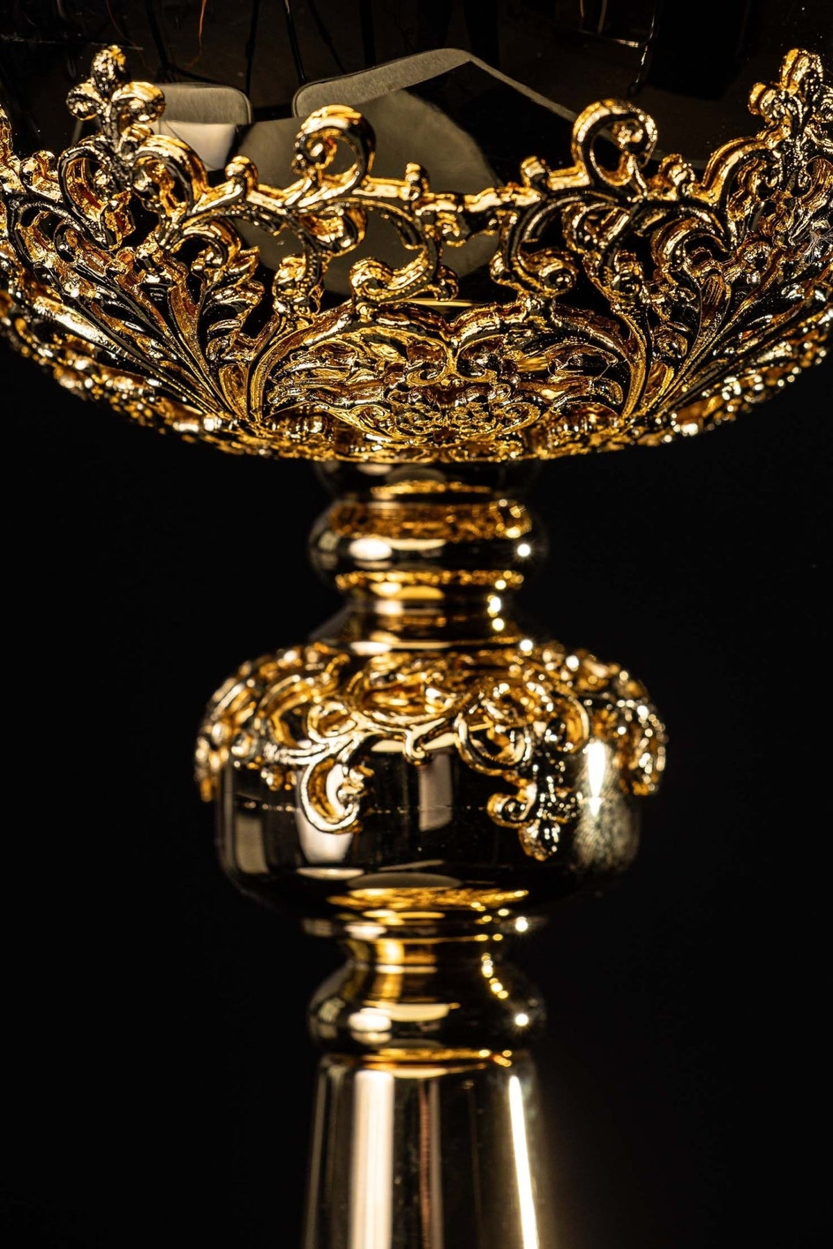 Gold-plated ciborium close-up of ornate floral scrollwork around the bowl and stem