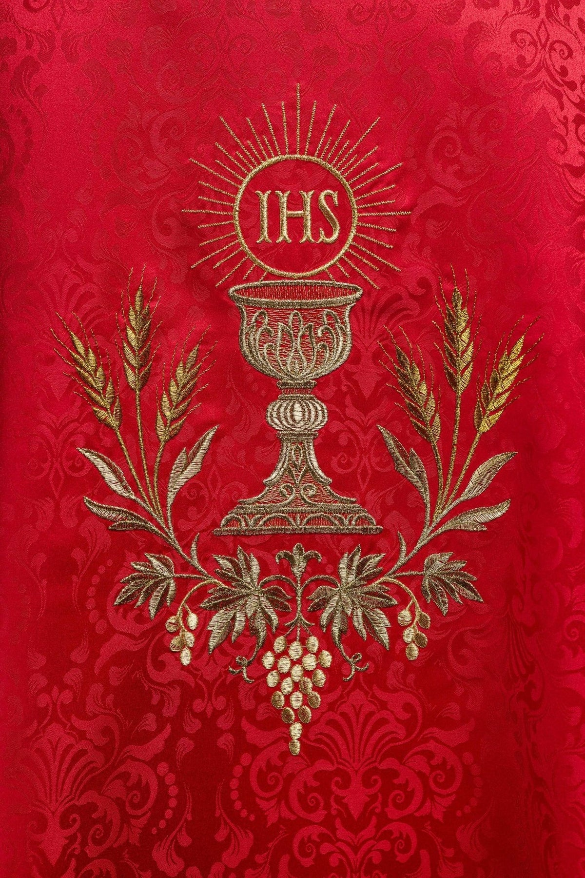 Red chasuble close-up with IHS monogram, chalice and wheat embroidery