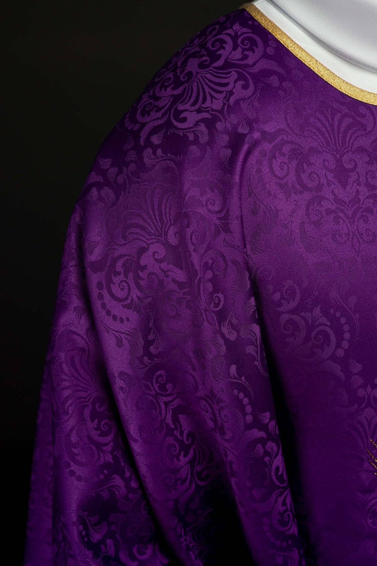 Purple chasuble close-up showing jacquard fabric and gold trim