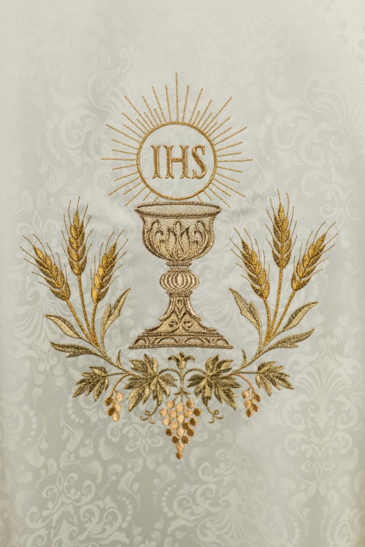 Ecru chasuble close-up showing gold IHS monogram, chalice, wheat and vine embroidery