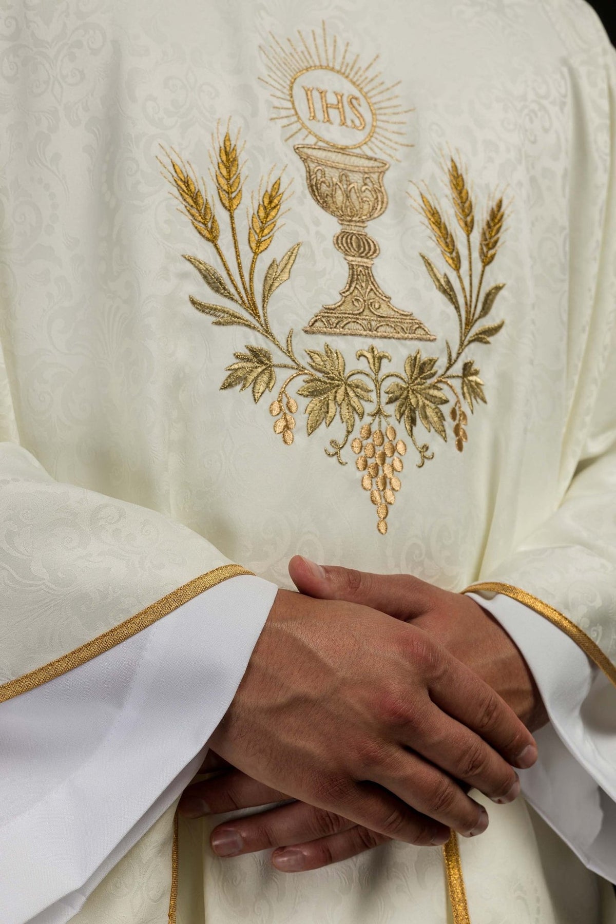 Ecru chasuble close-up showing Eucharistic embroidery and gold trim on the sleeve