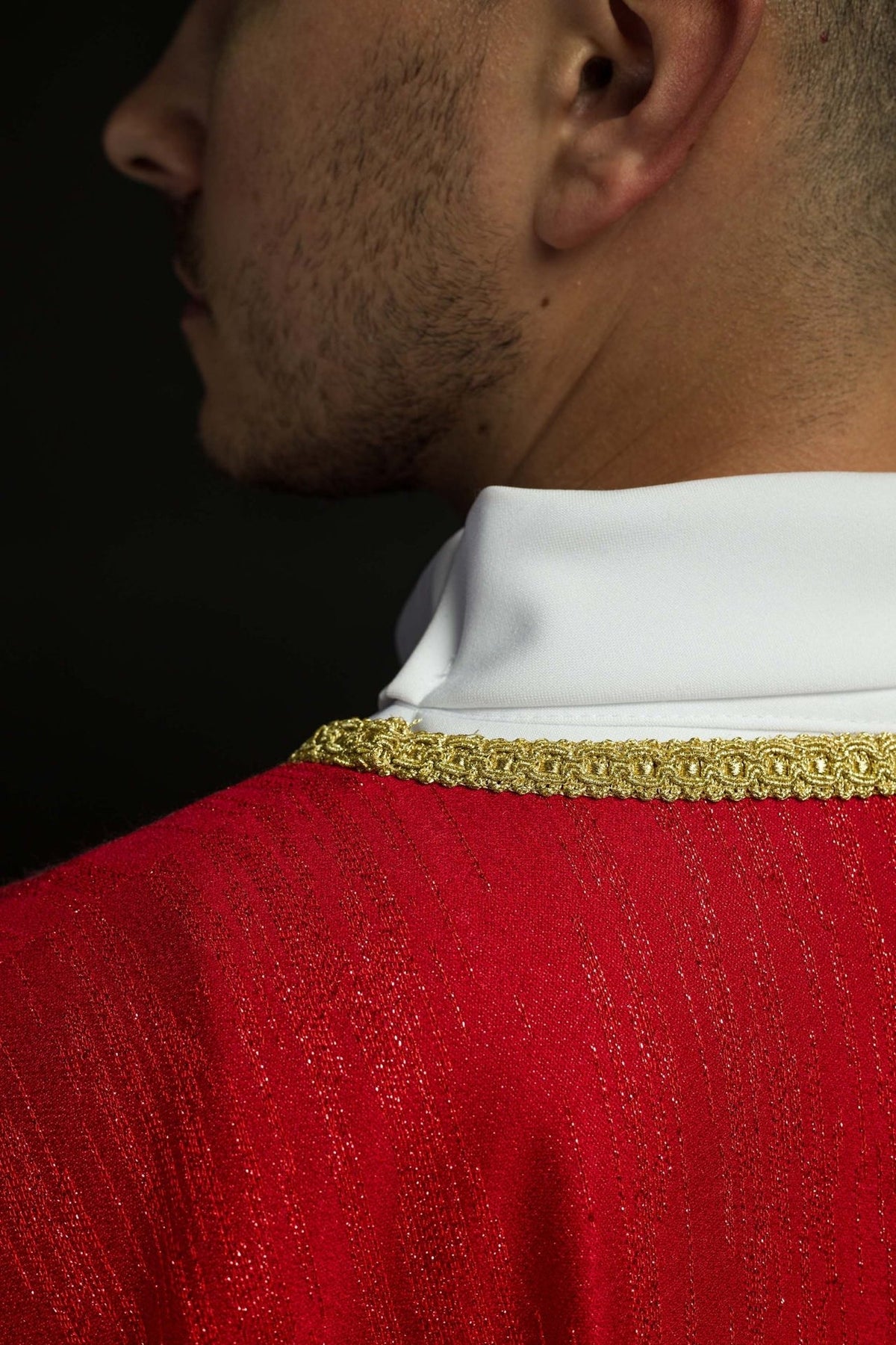 Red chasuble close-up showing gold neck trim and decorative fabric