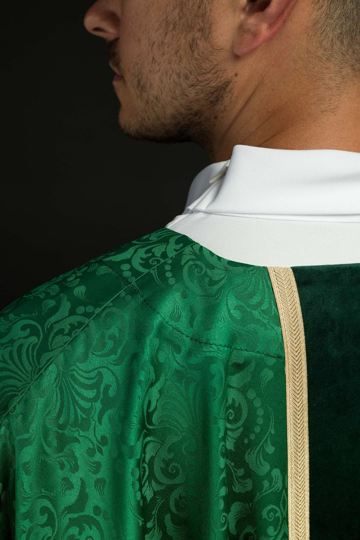 Green chasuble shoulder close-up showing jacquard fabric and gold trim