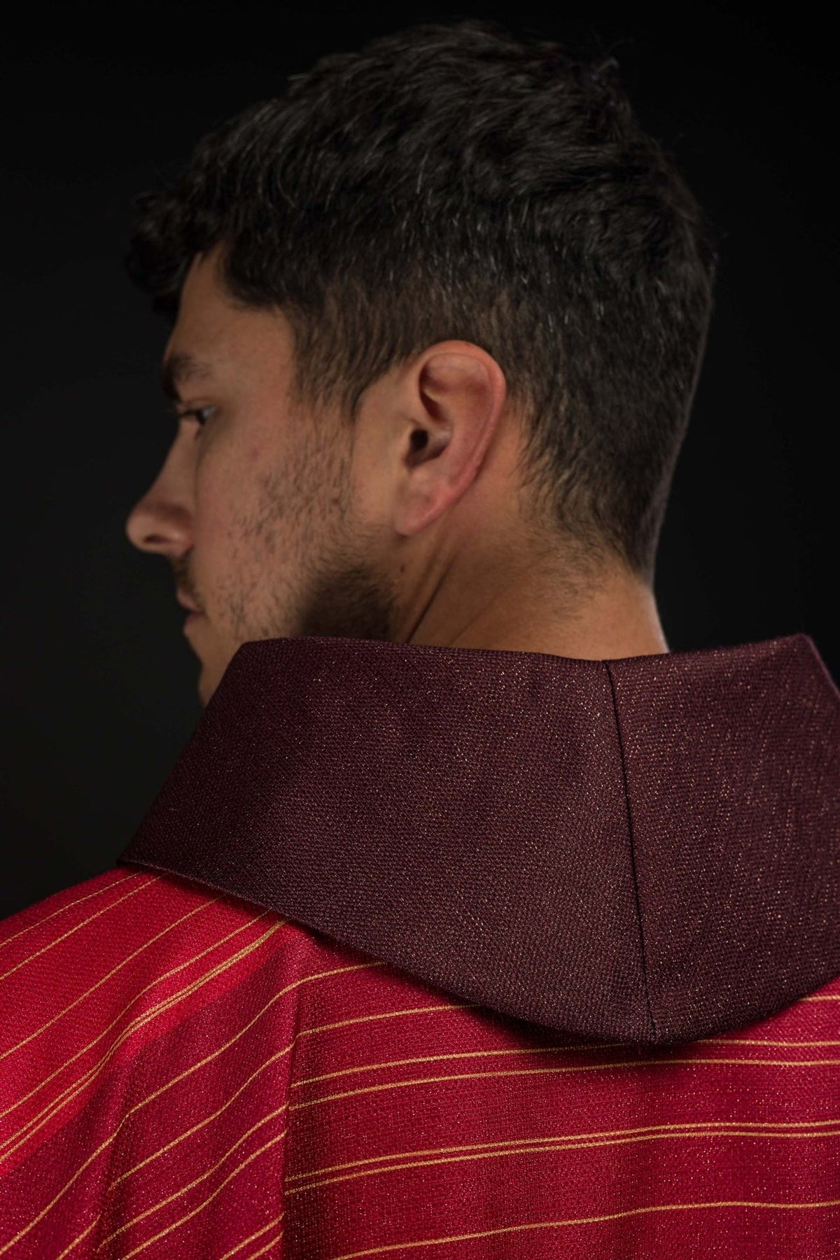 Red chasuble sleeve close-up with gold trim and striped fabric
