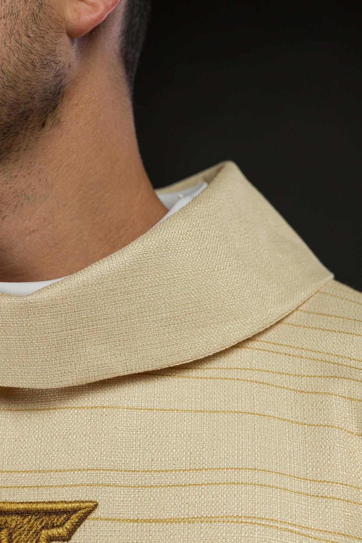 Ecru chasuble close-up showing gold trim at the sleeve edge