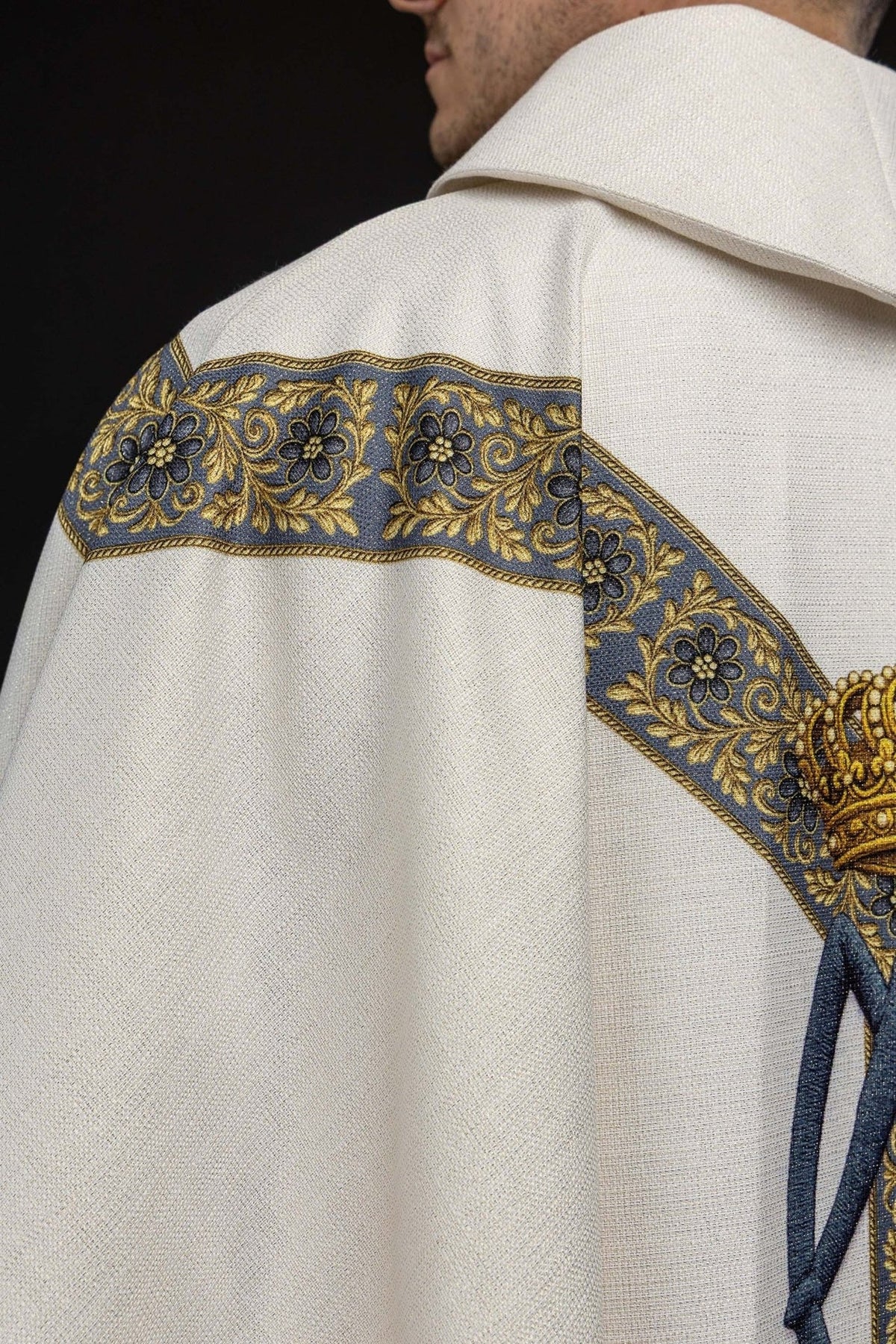 Marian chasuble shoulder close-up showing ecru fabric, blue floral trim and small gold cross