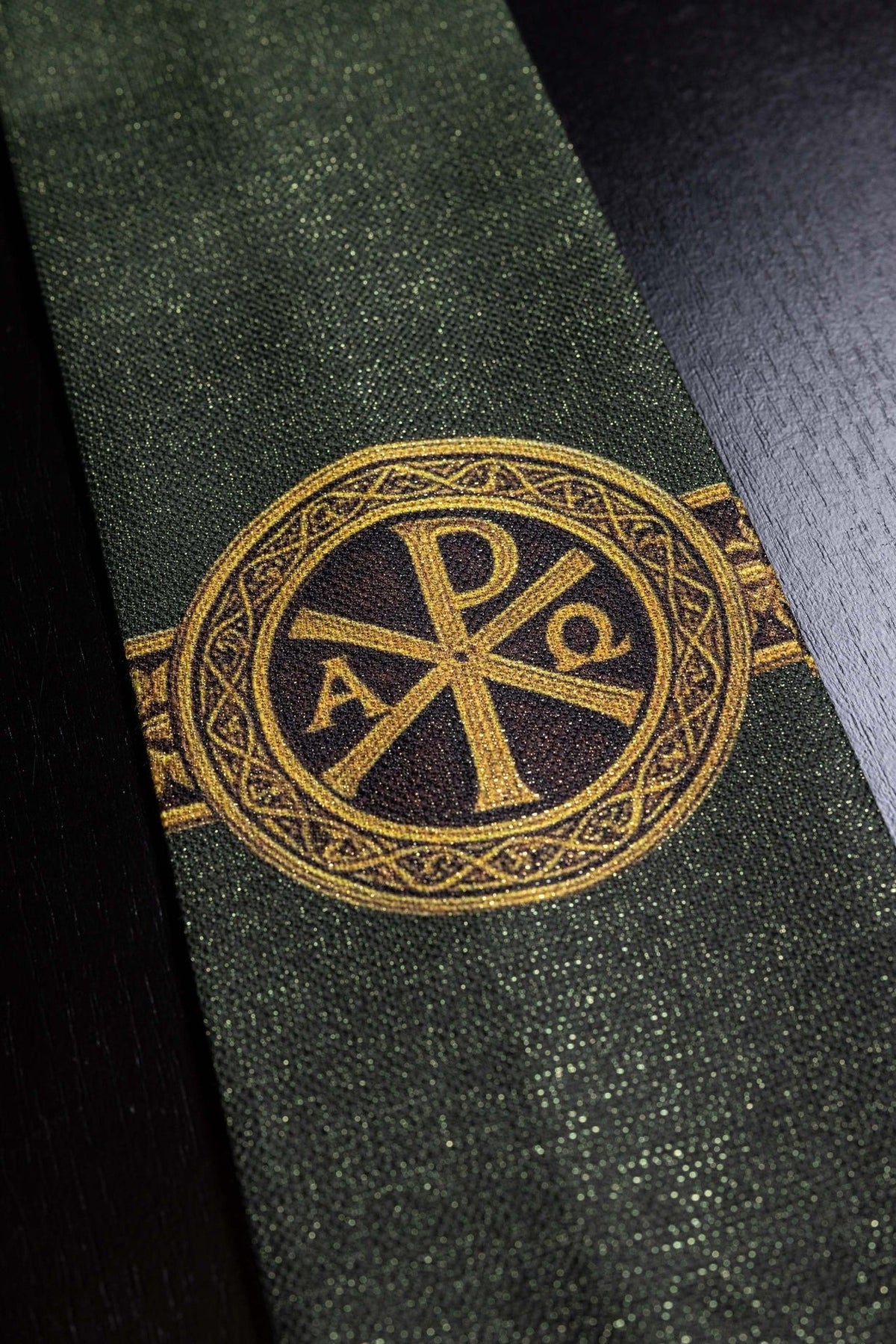 Green stole close-up showing the gold Pax cross motif and textured fabric
