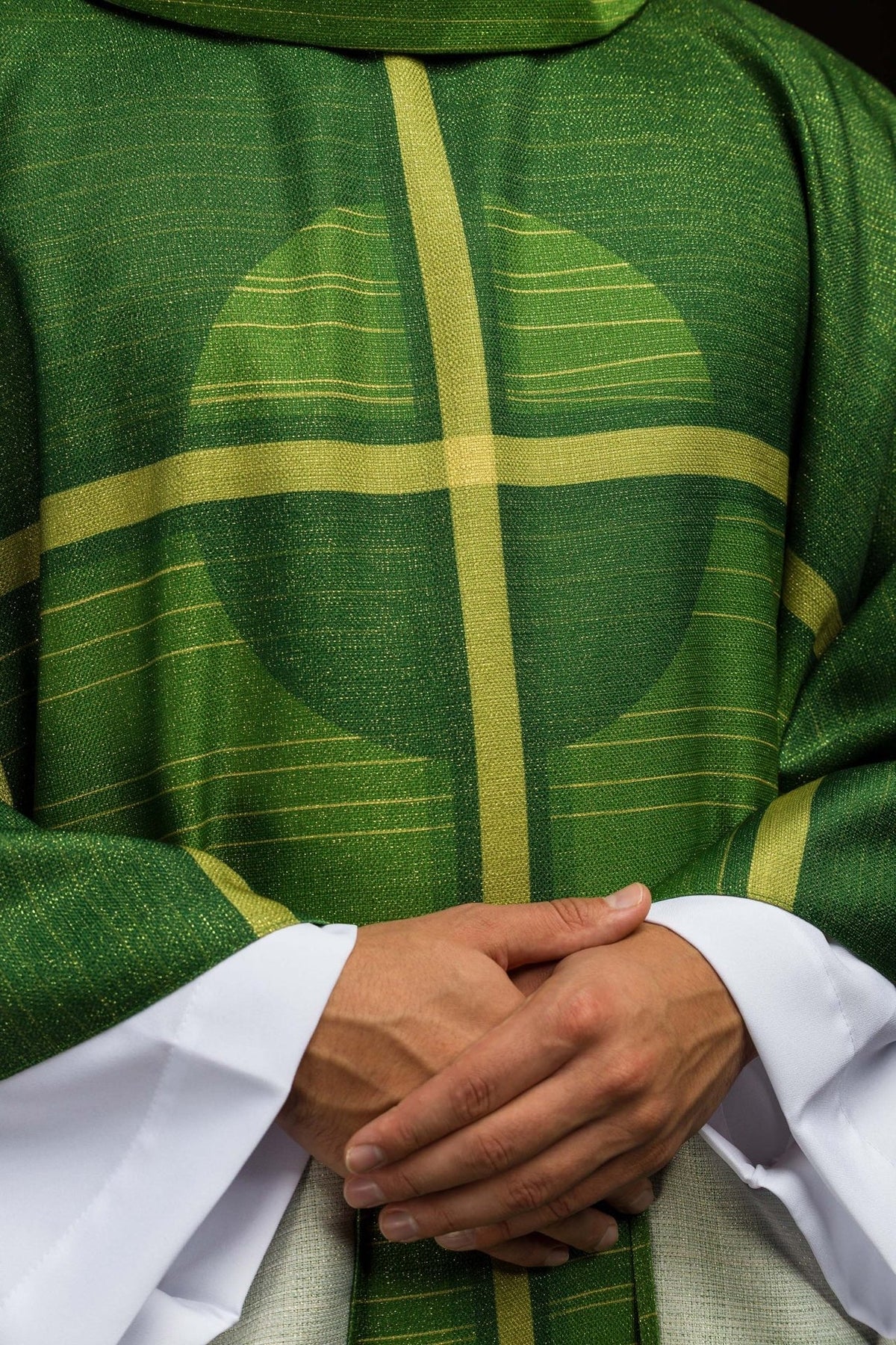 Green chasuble front close-up showing gold cross motif and textured fabric
