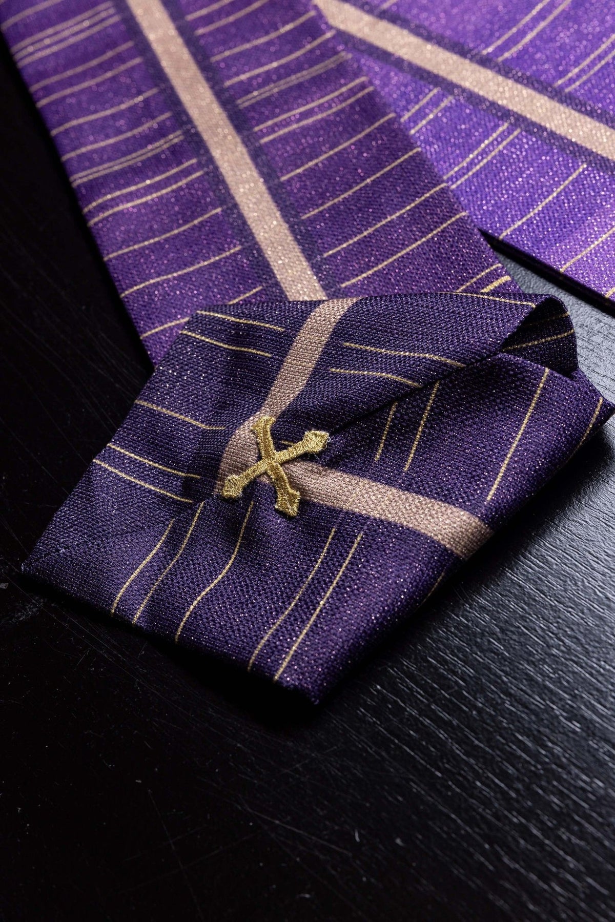 Purple printed Catholic chasuble close-up with gold cross motif and linear pattern