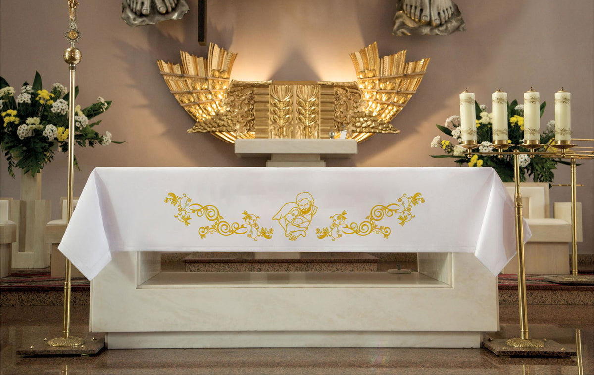 Embroidered altar cloth with an image of the Holy Family, white with gold embroidery, shown on an altar