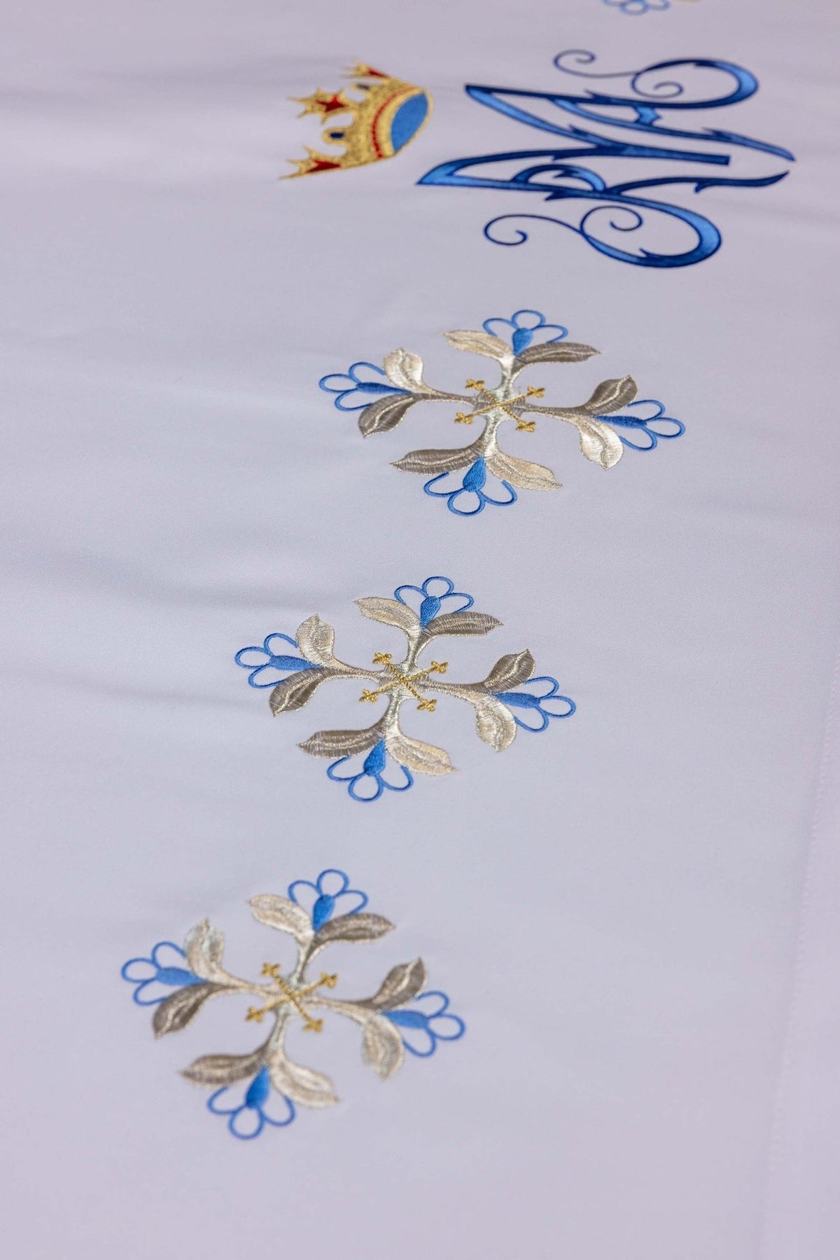 Altar cloth detail showing embroidered blue and silver floral Marian motifs