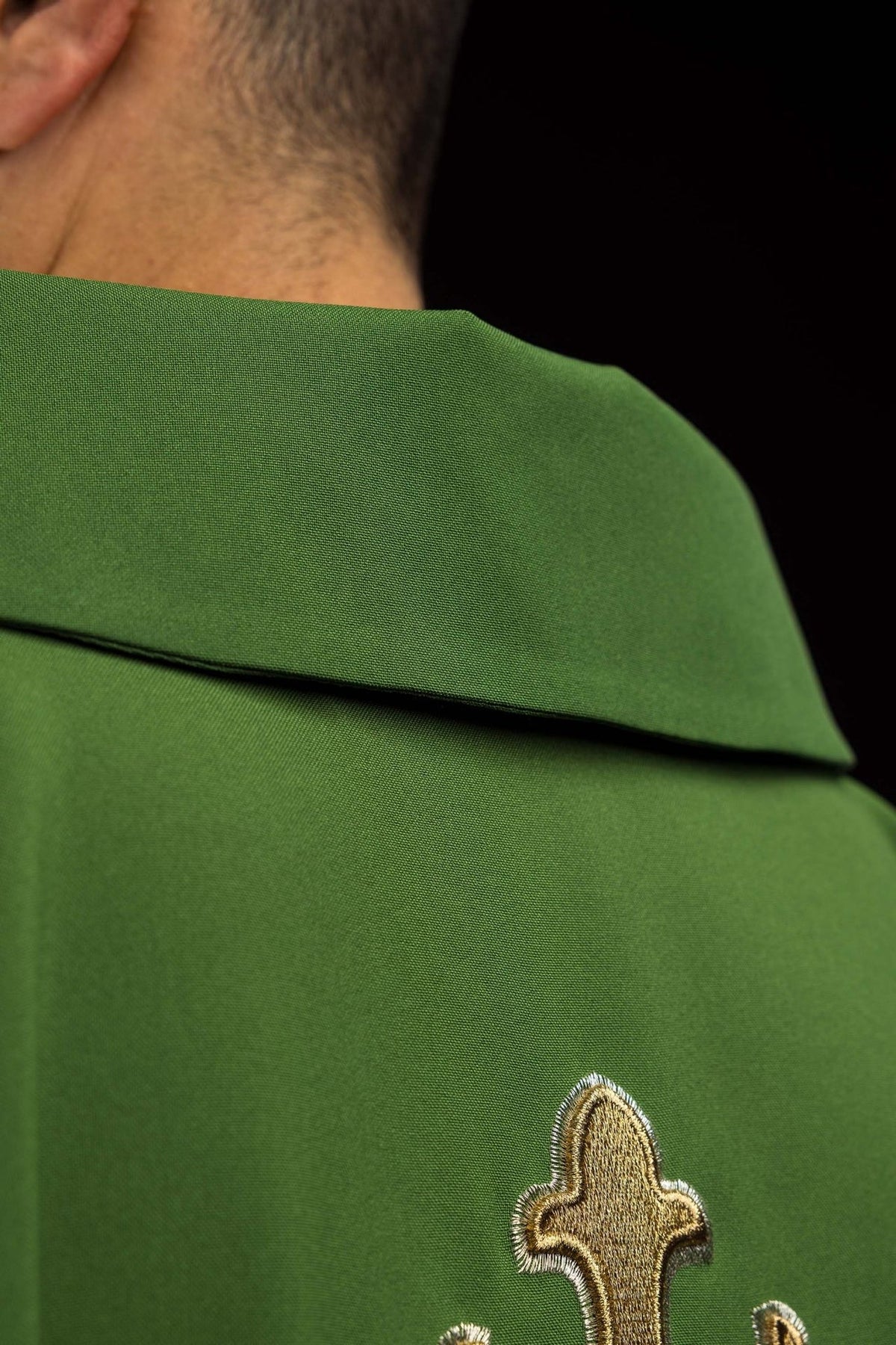 Green embroidered chasuble close-up showing wide collar and cross