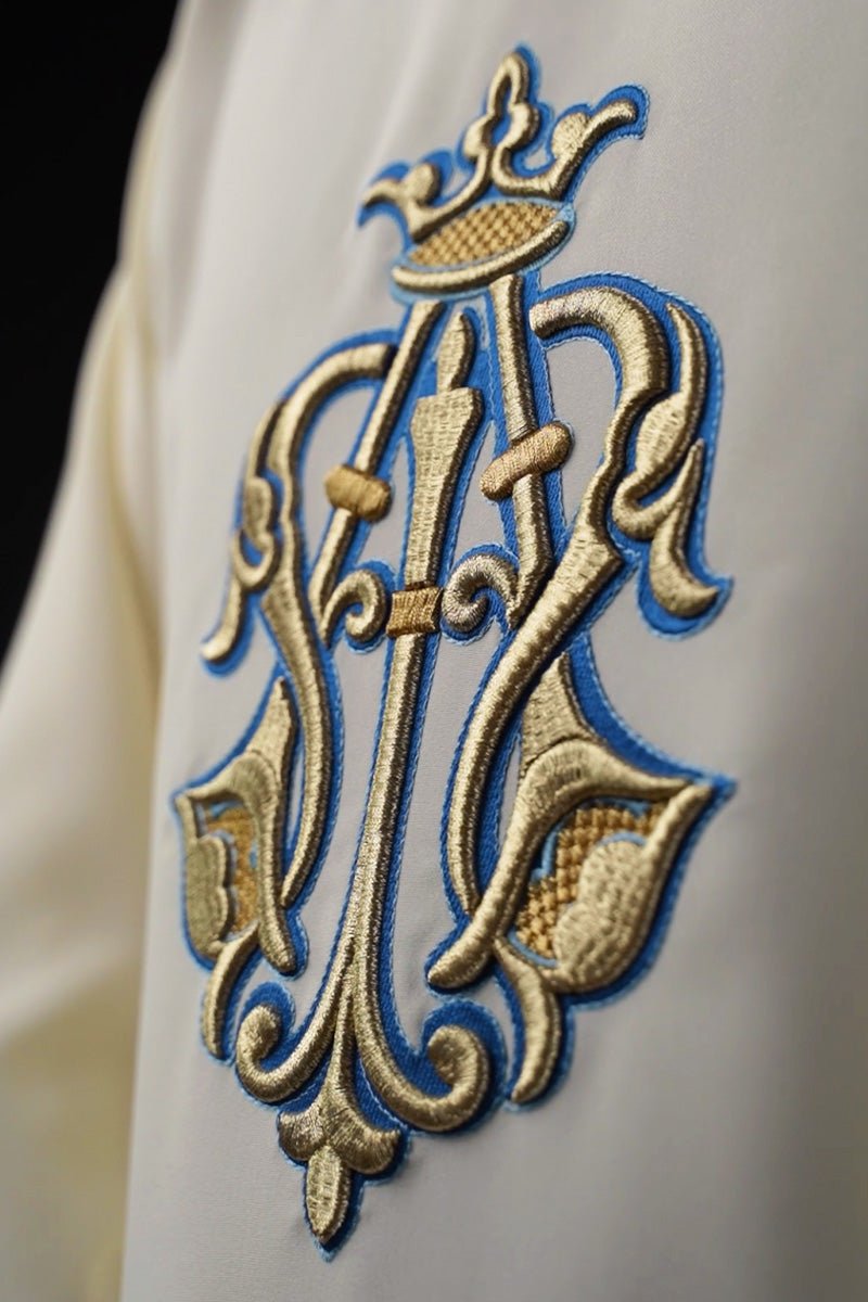 Chasuble close-up showing embroidered gold and blue Marian symbol