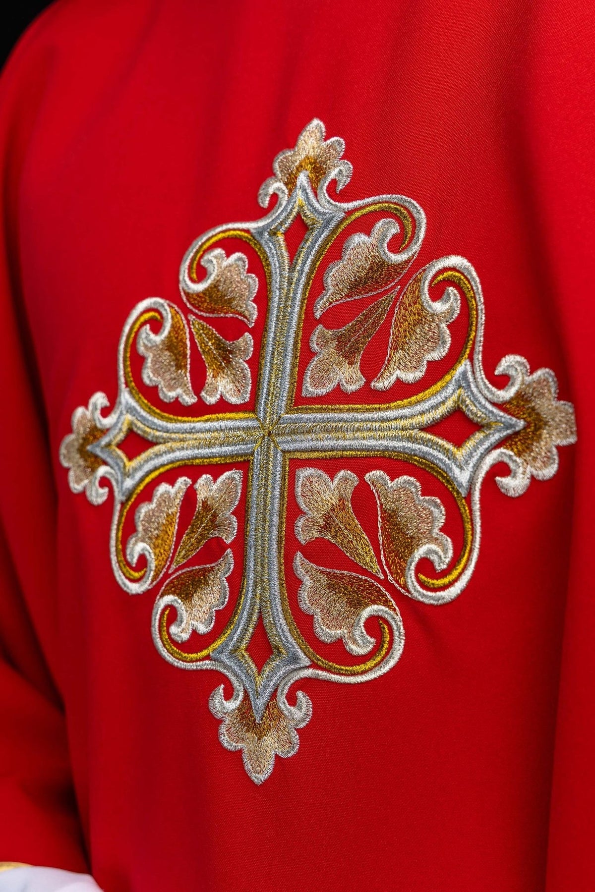 Red chasuble close-up showing embroidered gold cross