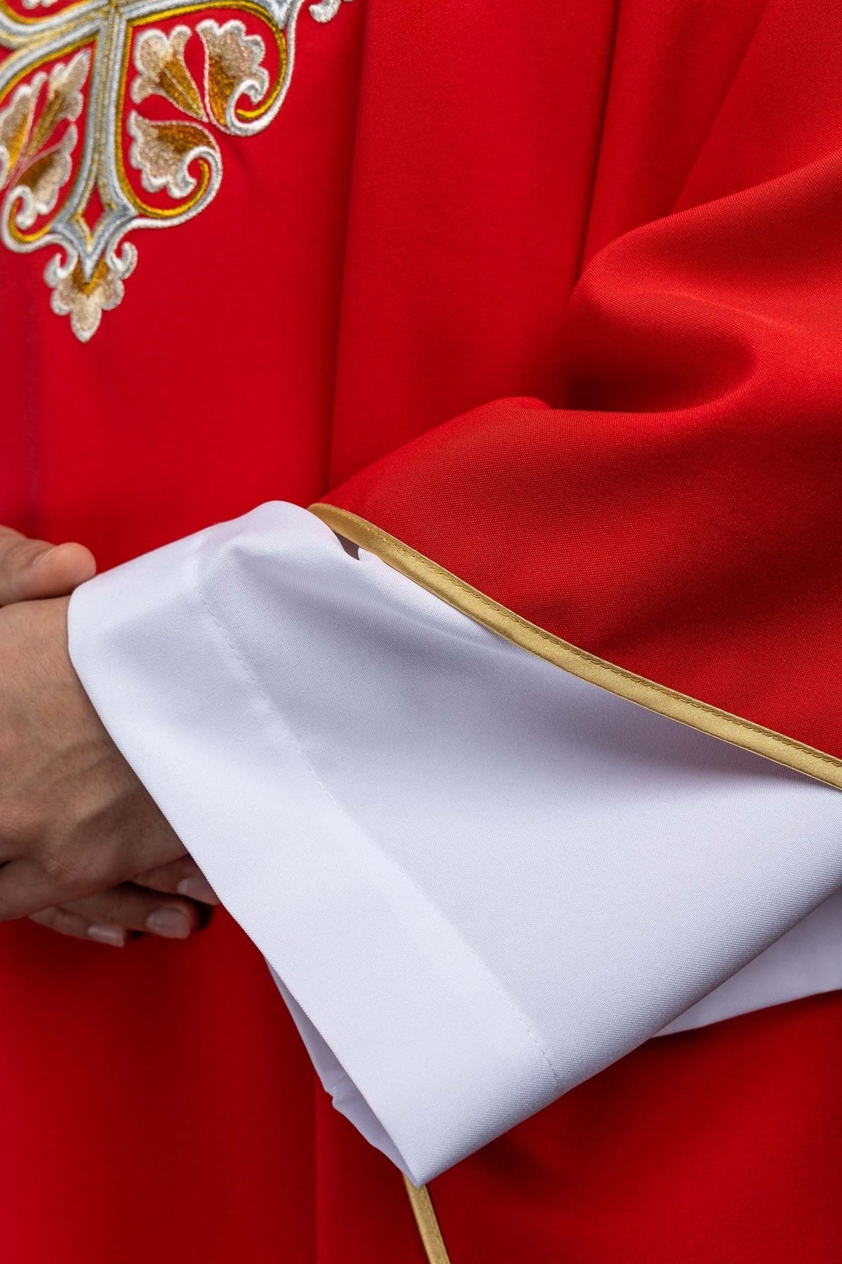 Red chasuble detail showing gold trim and white sleeve