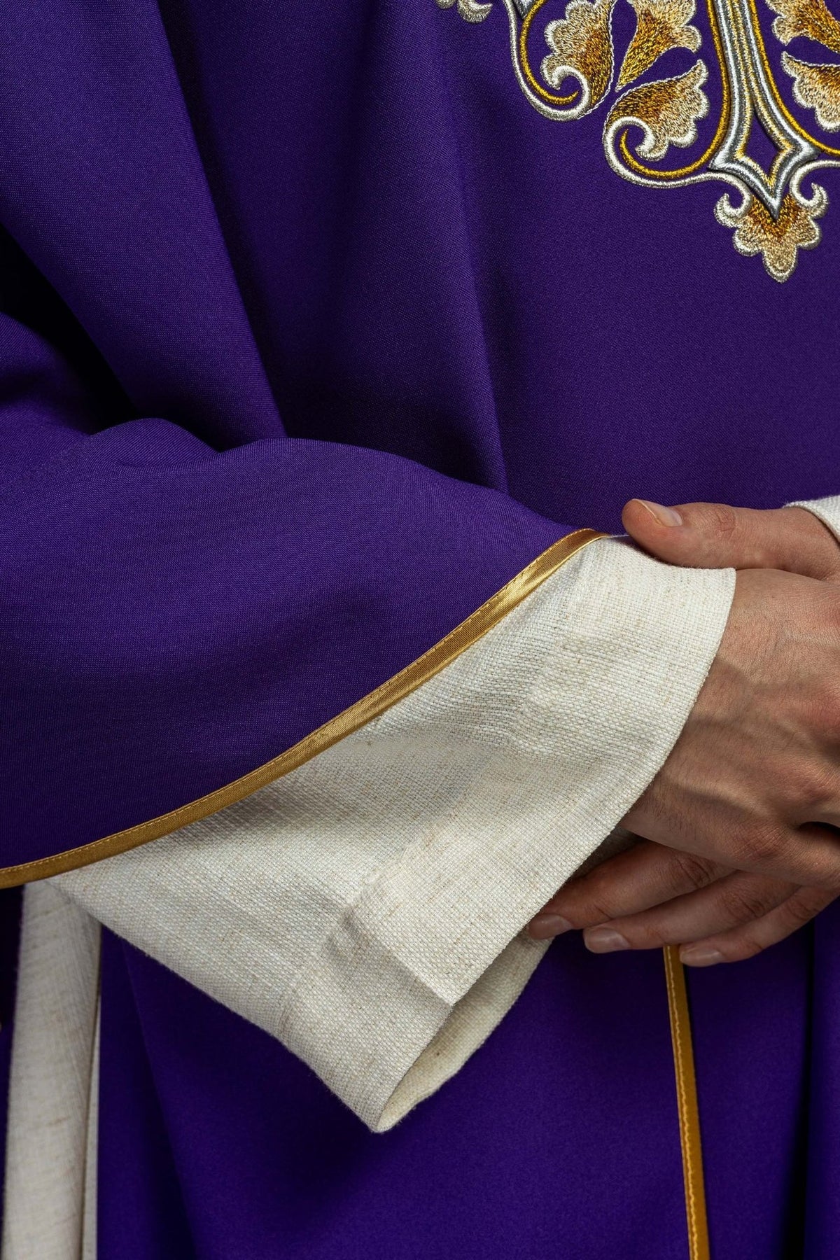 Purple chasuble detail showing gold trim on the sleeve edge