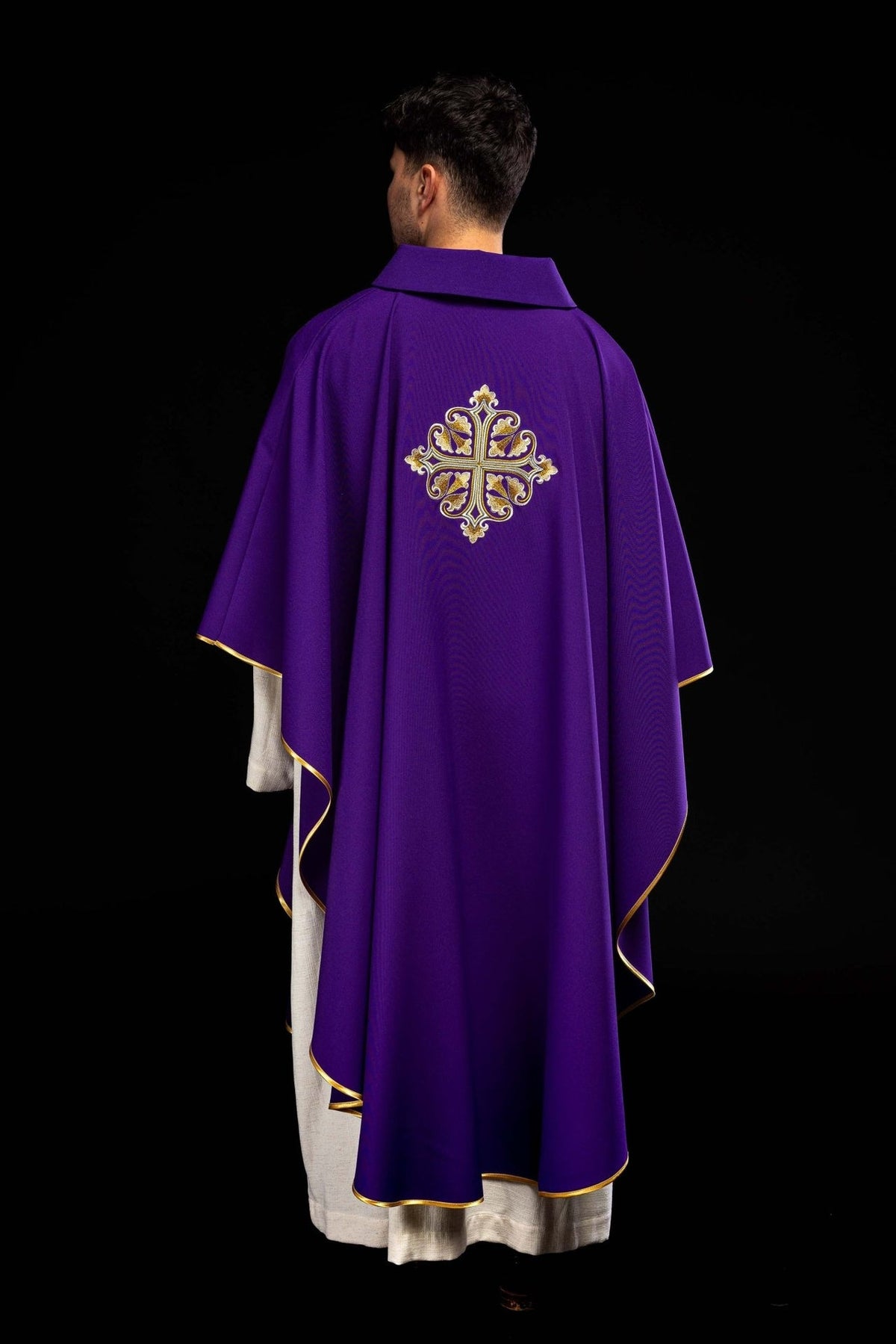 Purple chasuble back three-quarter view with gold trim and embroidered cross