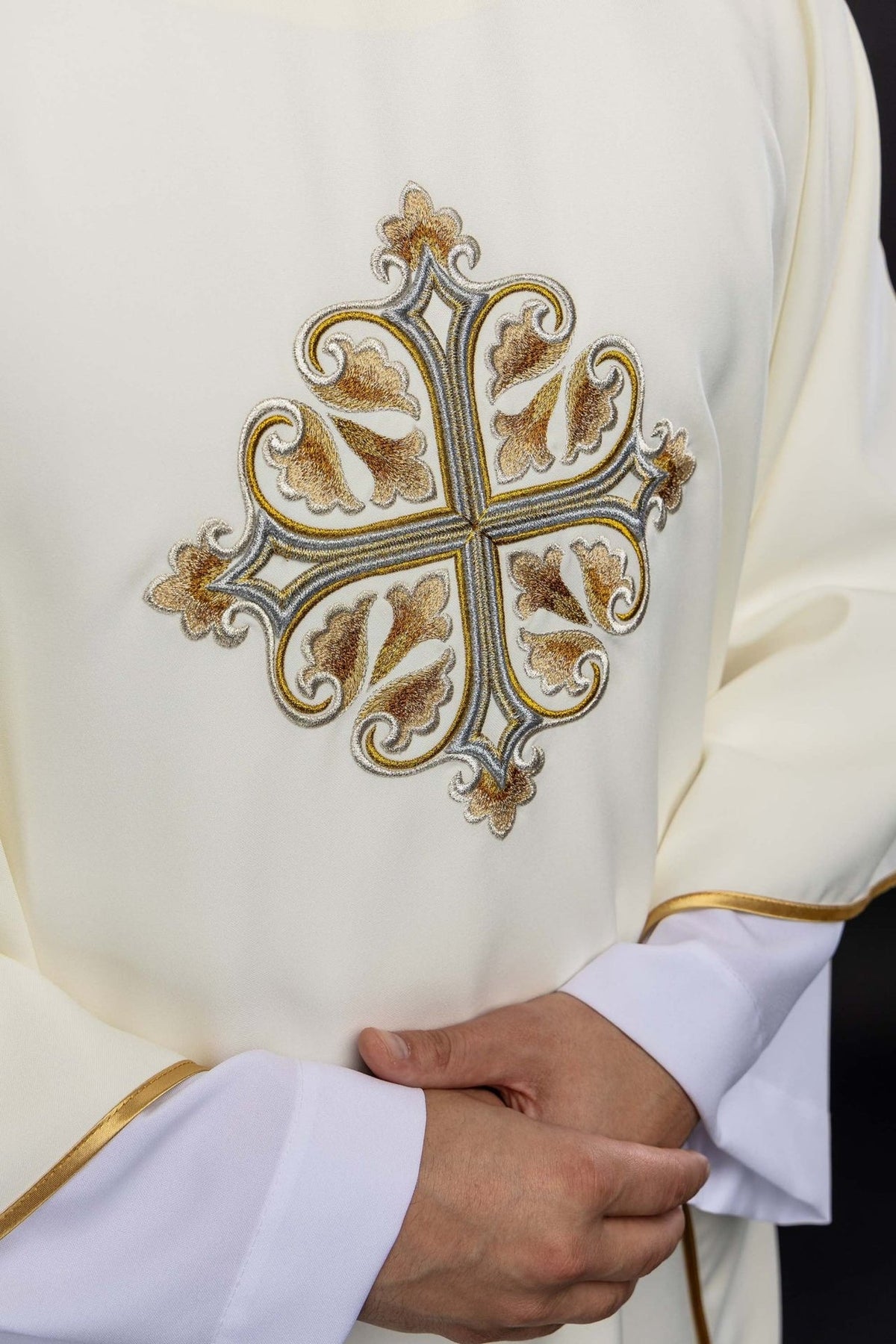 Ecru chasuble close-up with ornate embroidered cross and gold sleeve trim