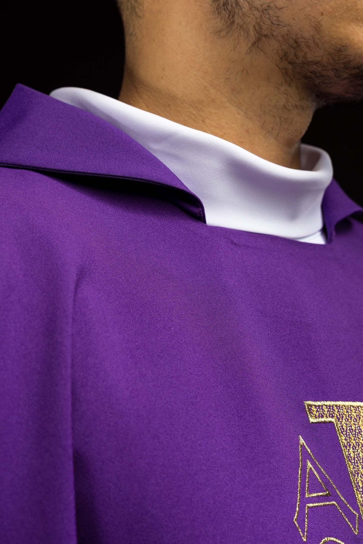 Purple chasuble close-up showing wide collar and gold Alpha Omega embroidery