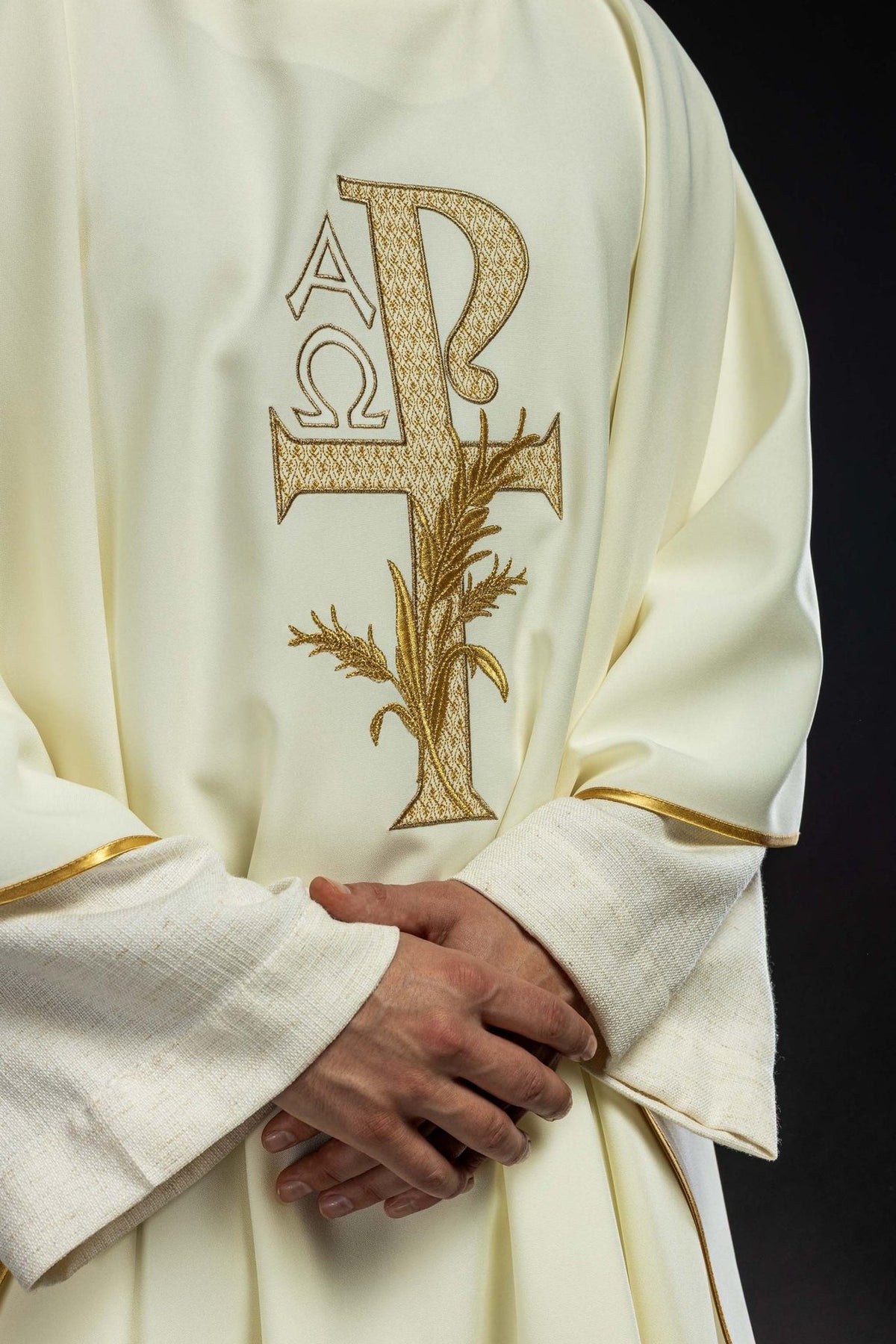 Embroidered chasuble close-up showing gold Alpha Omega cross embroidery and gold trim