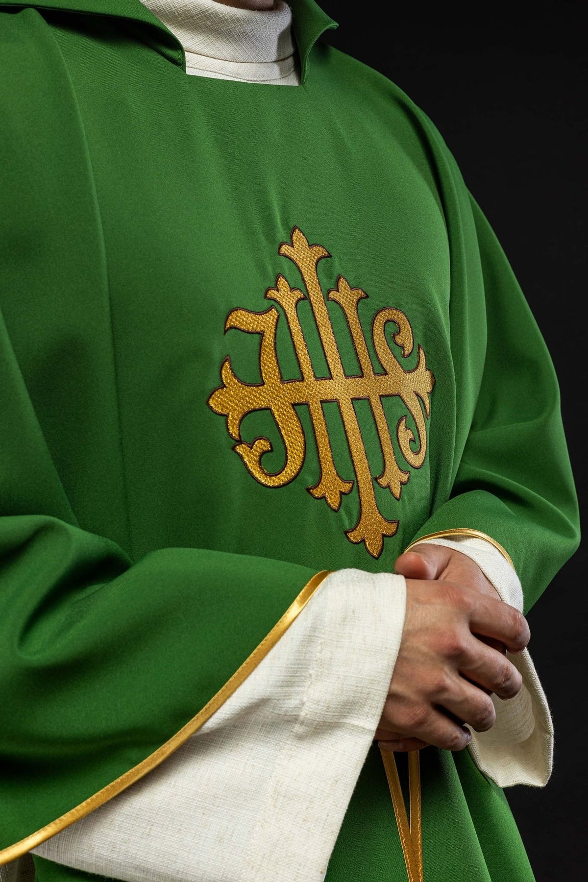 Green chasuble close-up showing gold JHS embroidery and sleeve trim