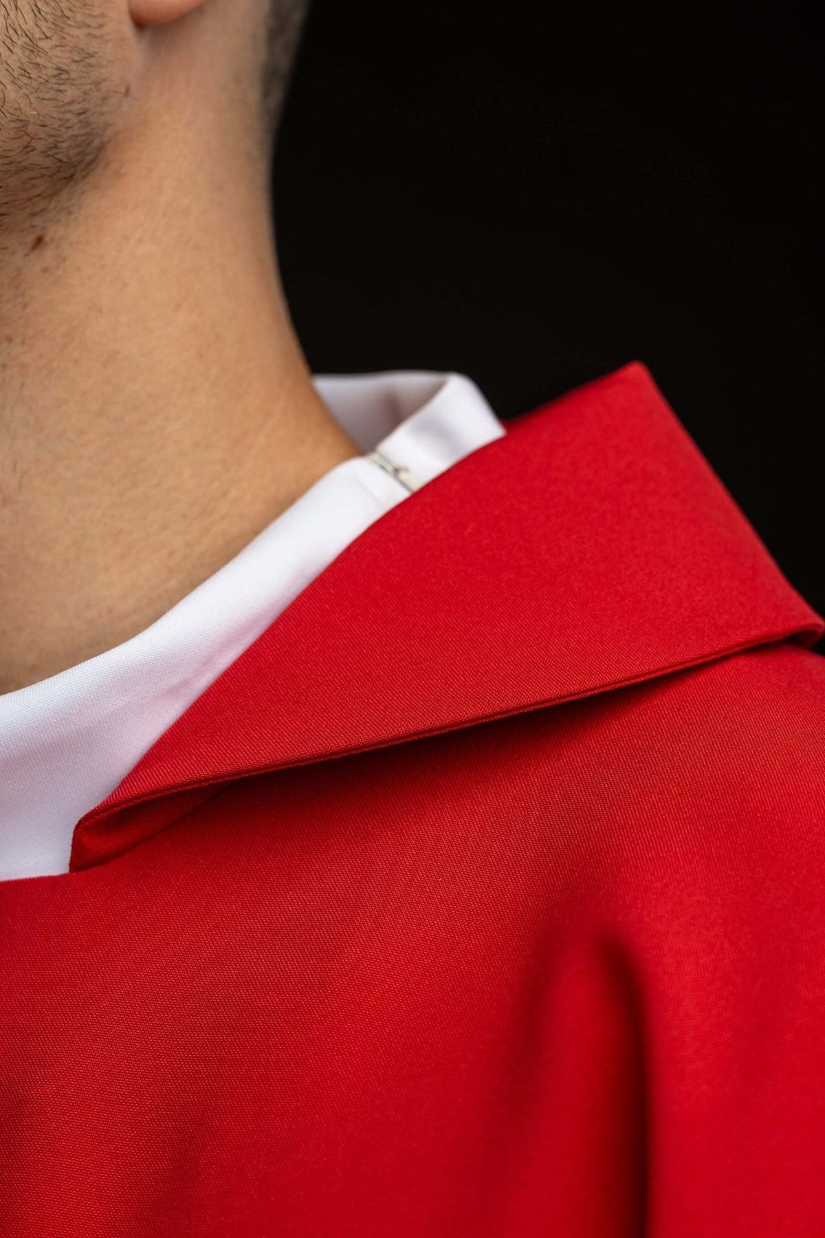 Red chasuble close-up showing the wide collar and gold JHS embroidery