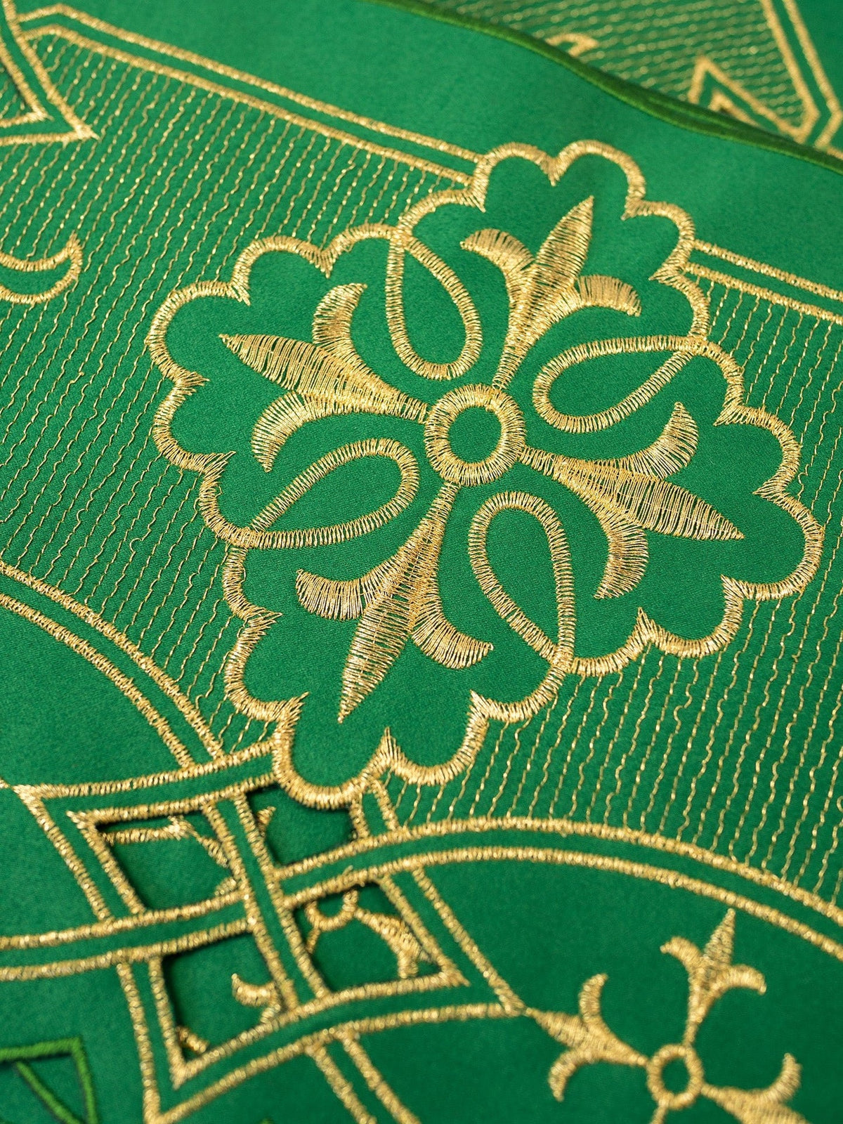 Green altar lace close-up showing gold rosette embroidery and geometric motifs