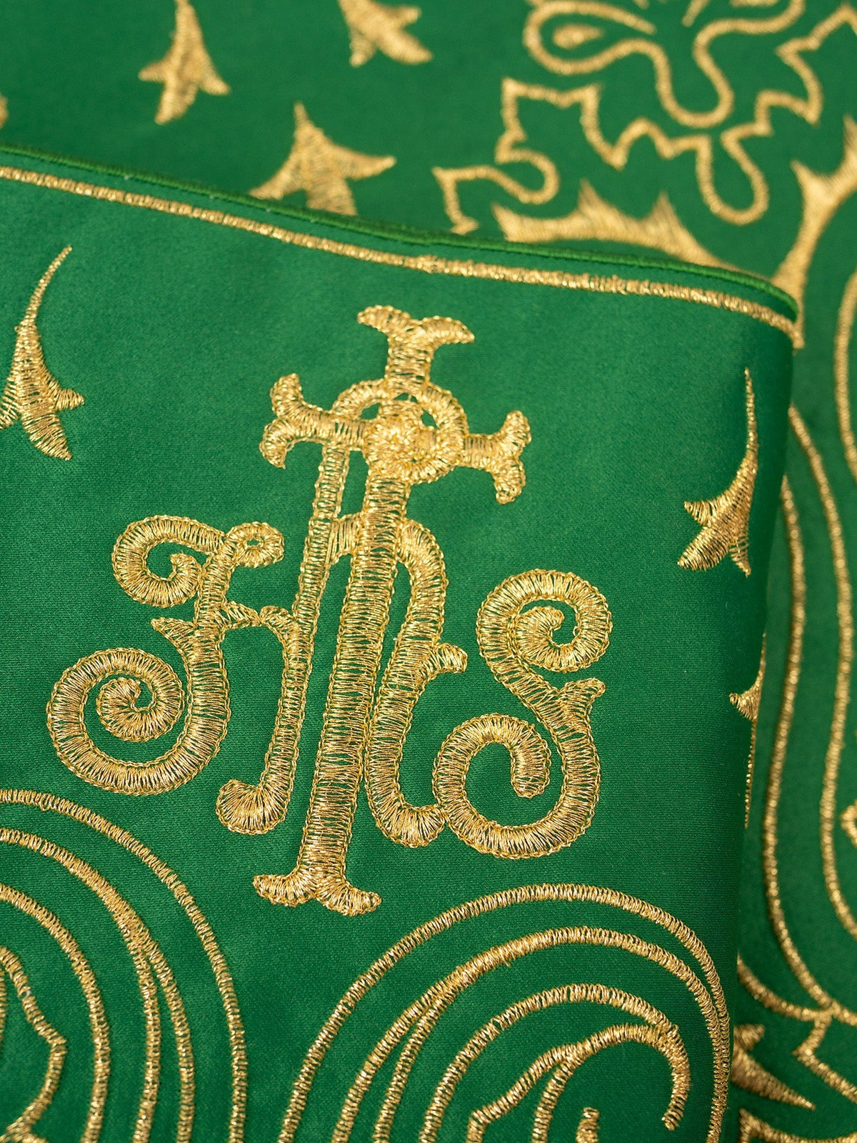 Green altar lace close-up showing gold IHS embroidery and decorative motifs