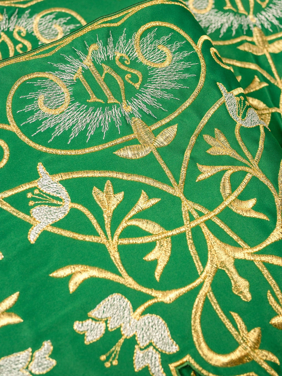 Green altar lace close-up showing embroidered IHS monogram and floral details