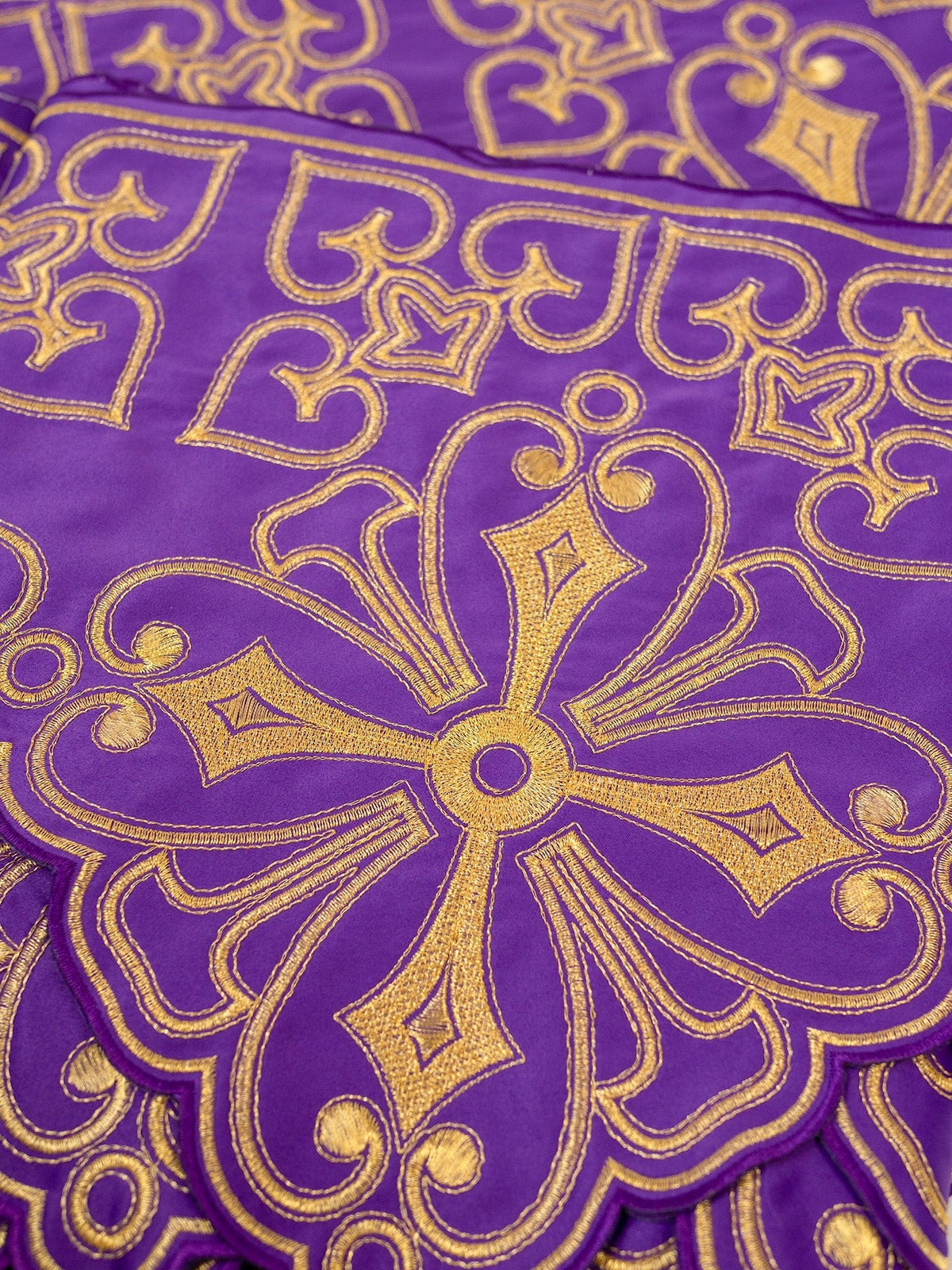 Purple altar lace close-up showing gold rosette embroidery and ornate scrolling details