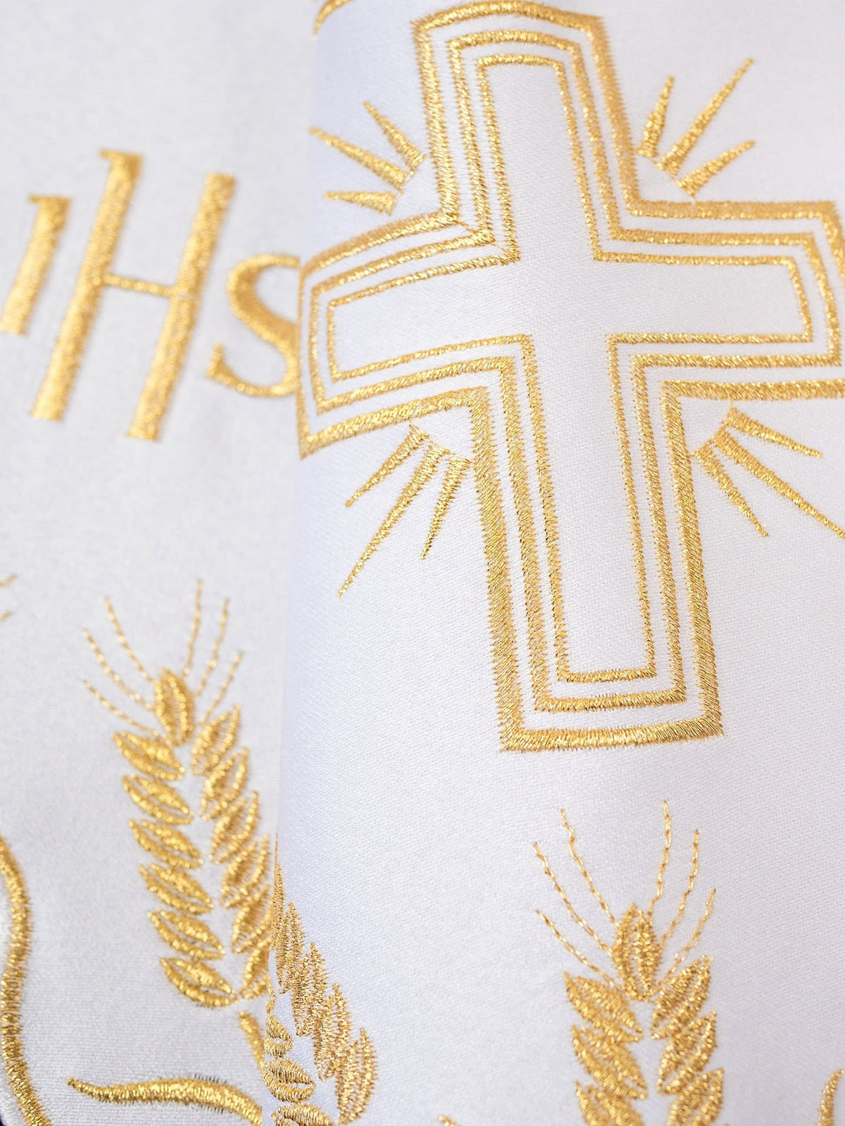 Altar lace close-up with embroidered gold IHS monogram and cross motif