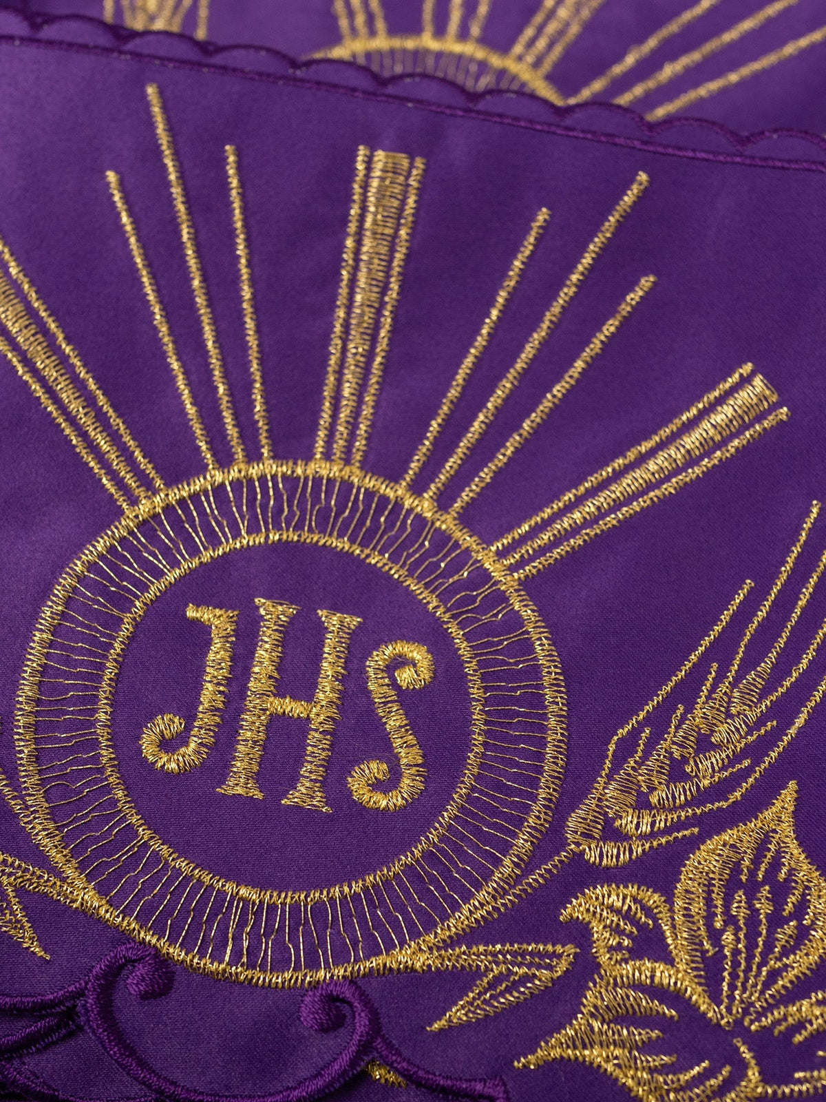 Altar lace close-up showing gold IHS embroidery, radiant rays and wheat motif