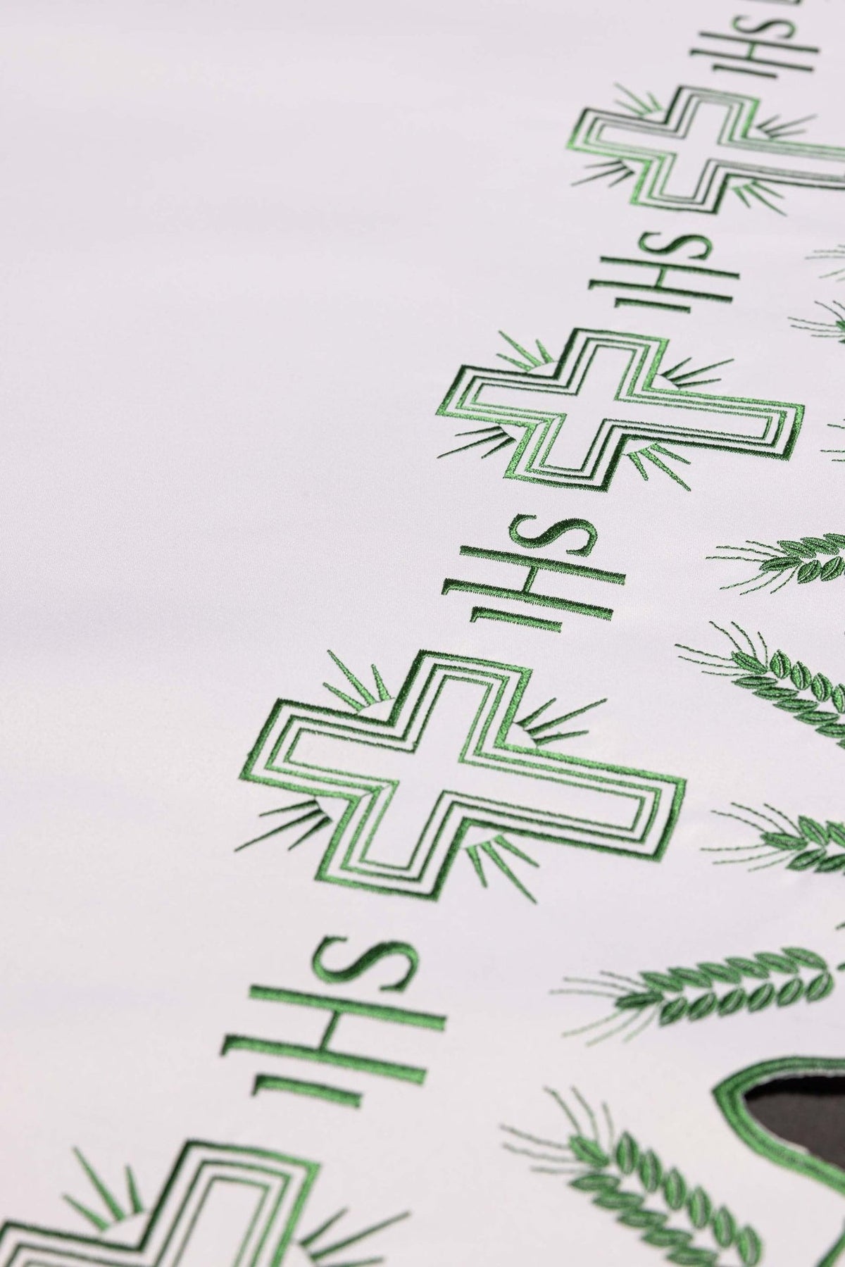 Altar cloth close-up showing green cross embroidery and IHS motifs