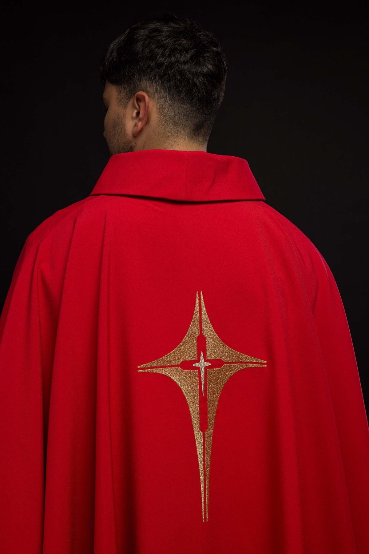 Red chasuble worn from the back with gold embroidered cross