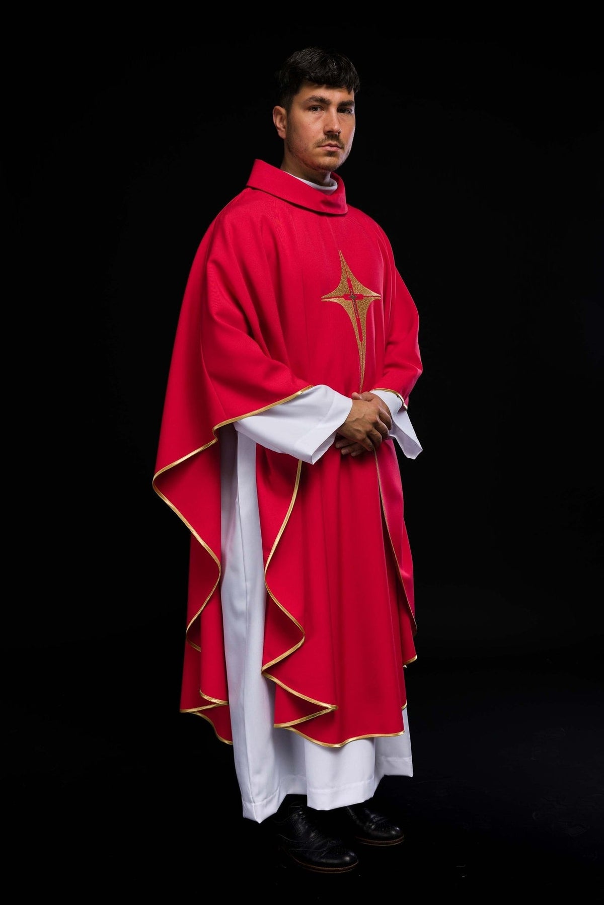Red chasuble worn from the side with gold trim and cross embroidery