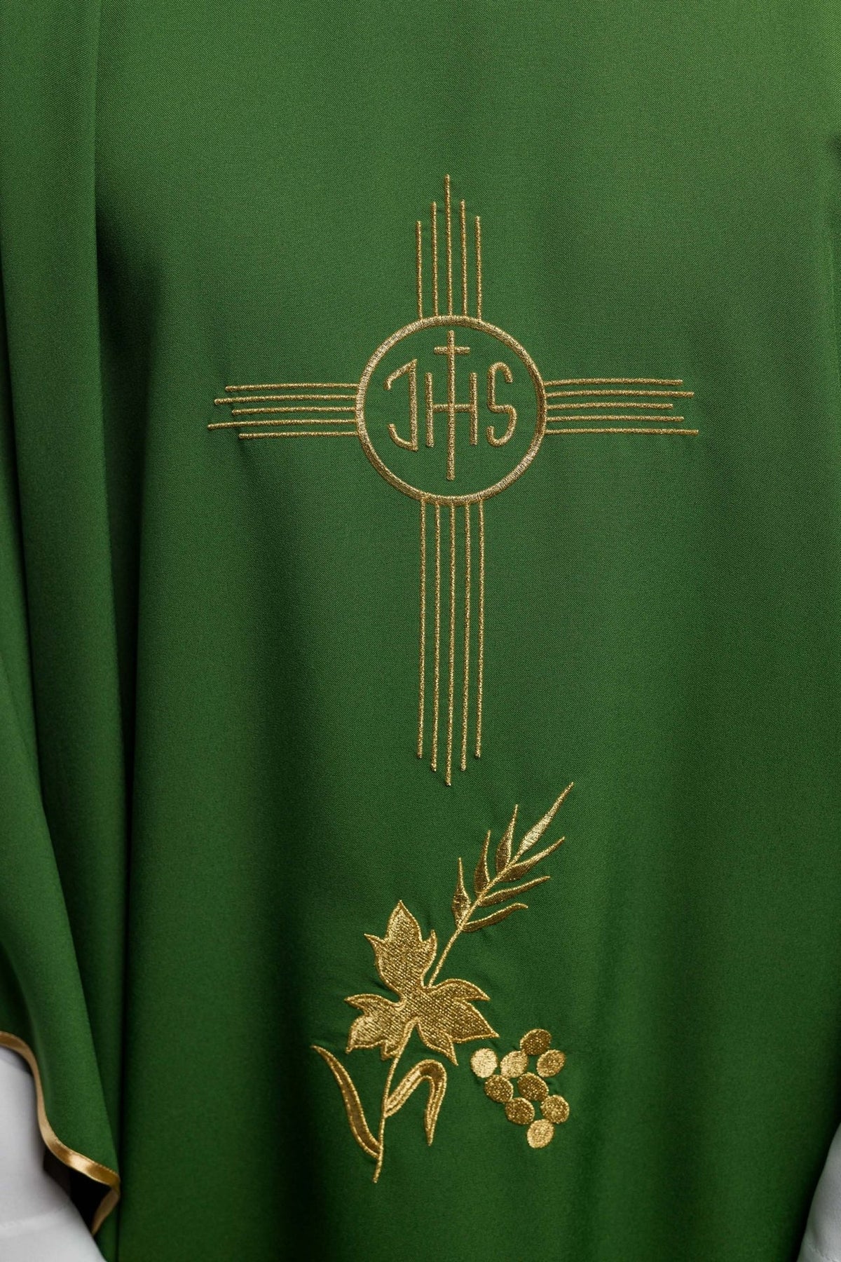 Green chasuble close-up showing gold IHS embroidery and floral embroidery