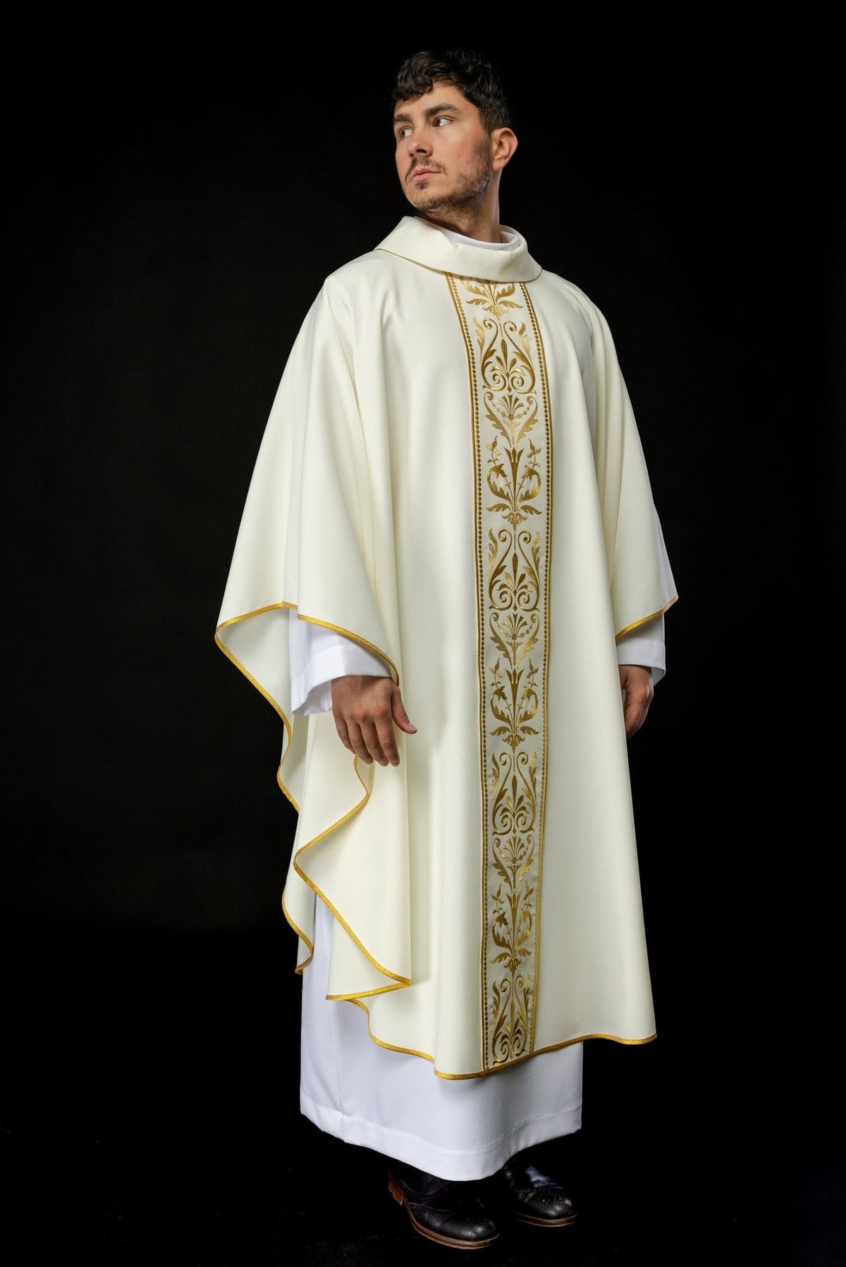 Ecru chasuble worn full length from the front, with gold embroidered orphrey and trim