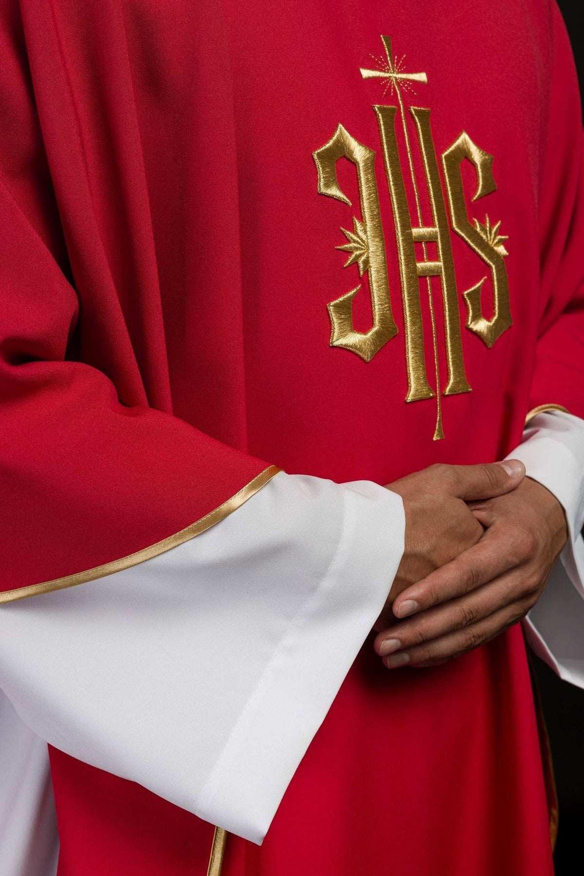 Red chasuble detail showing gold IHS embroidery and satin trim