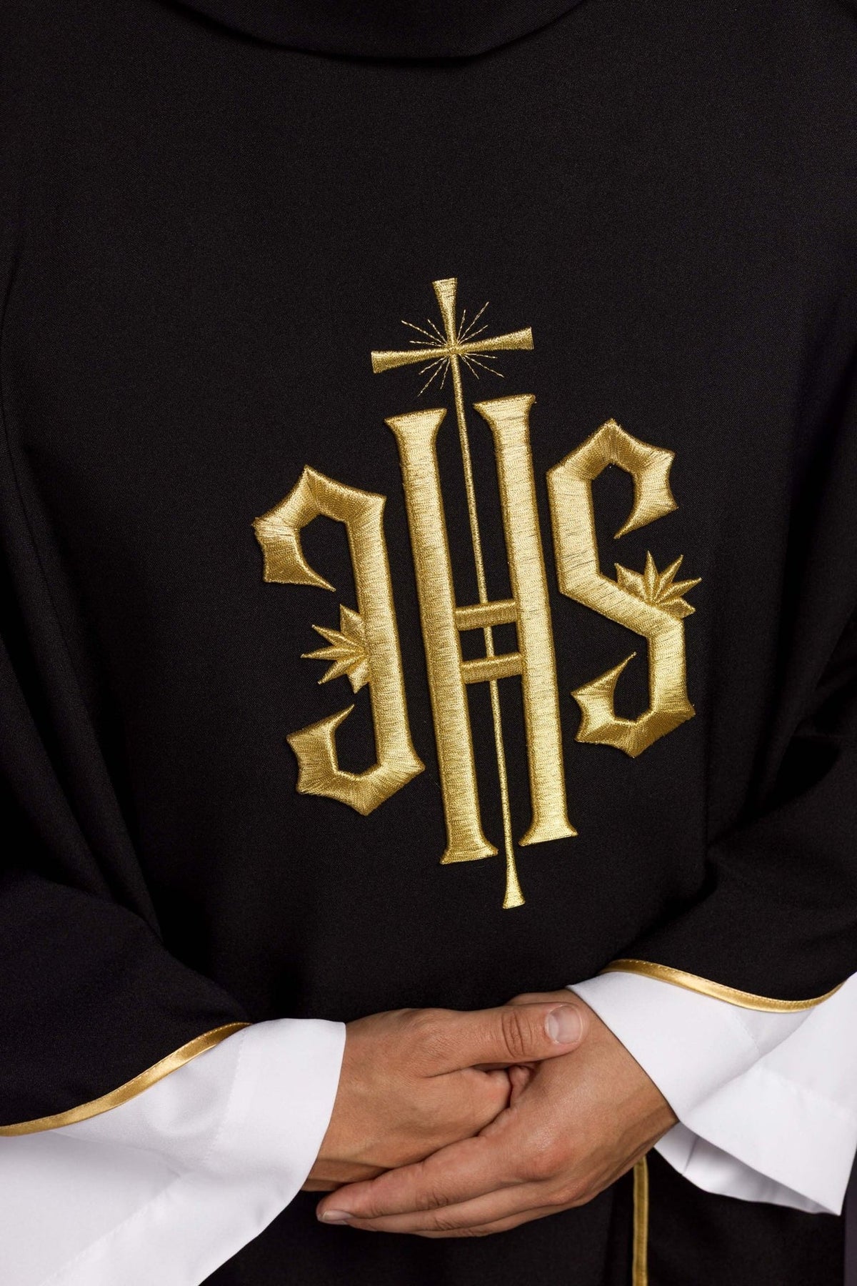 Black chasuble close-up showing gold embroidered IHS symbol and trim