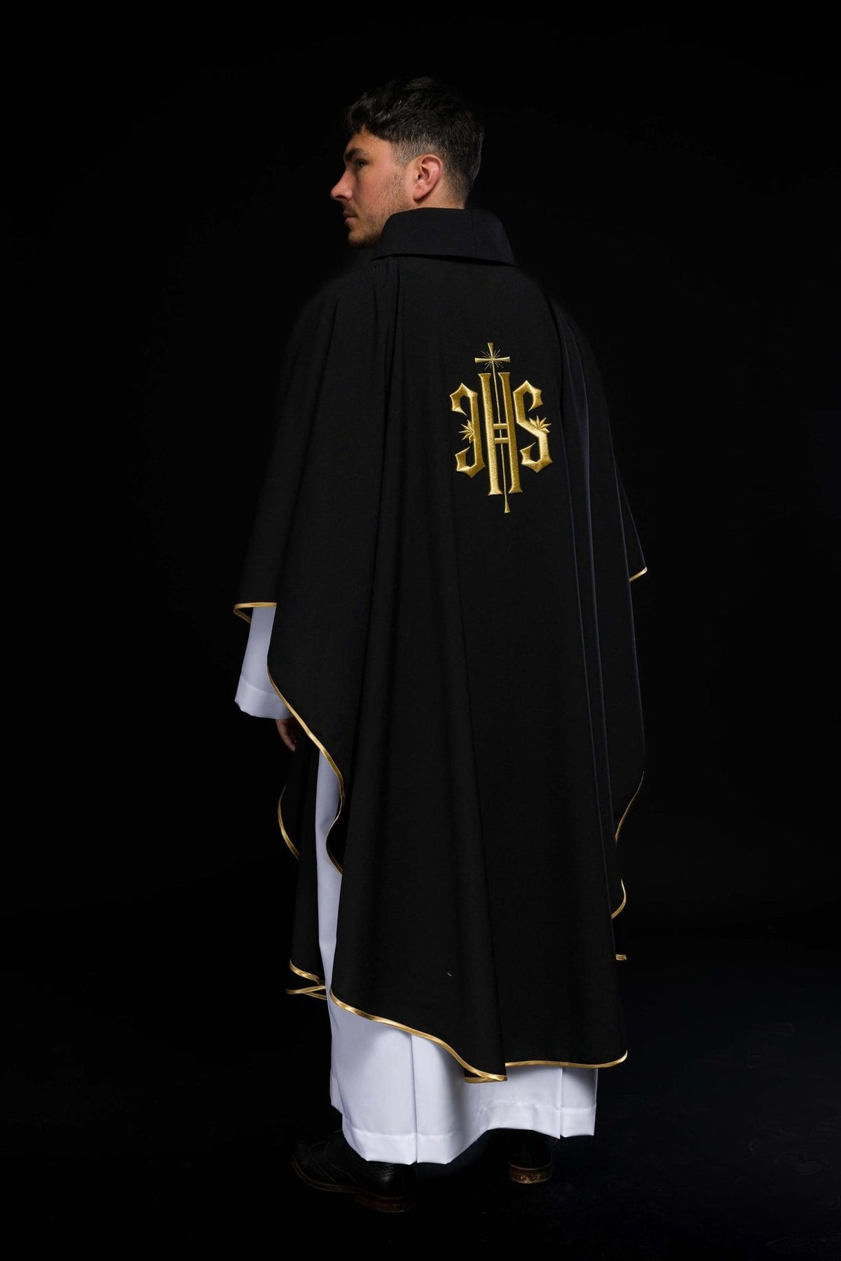 Black chasuble three-quarter back view with gold trim and IHS embroidery