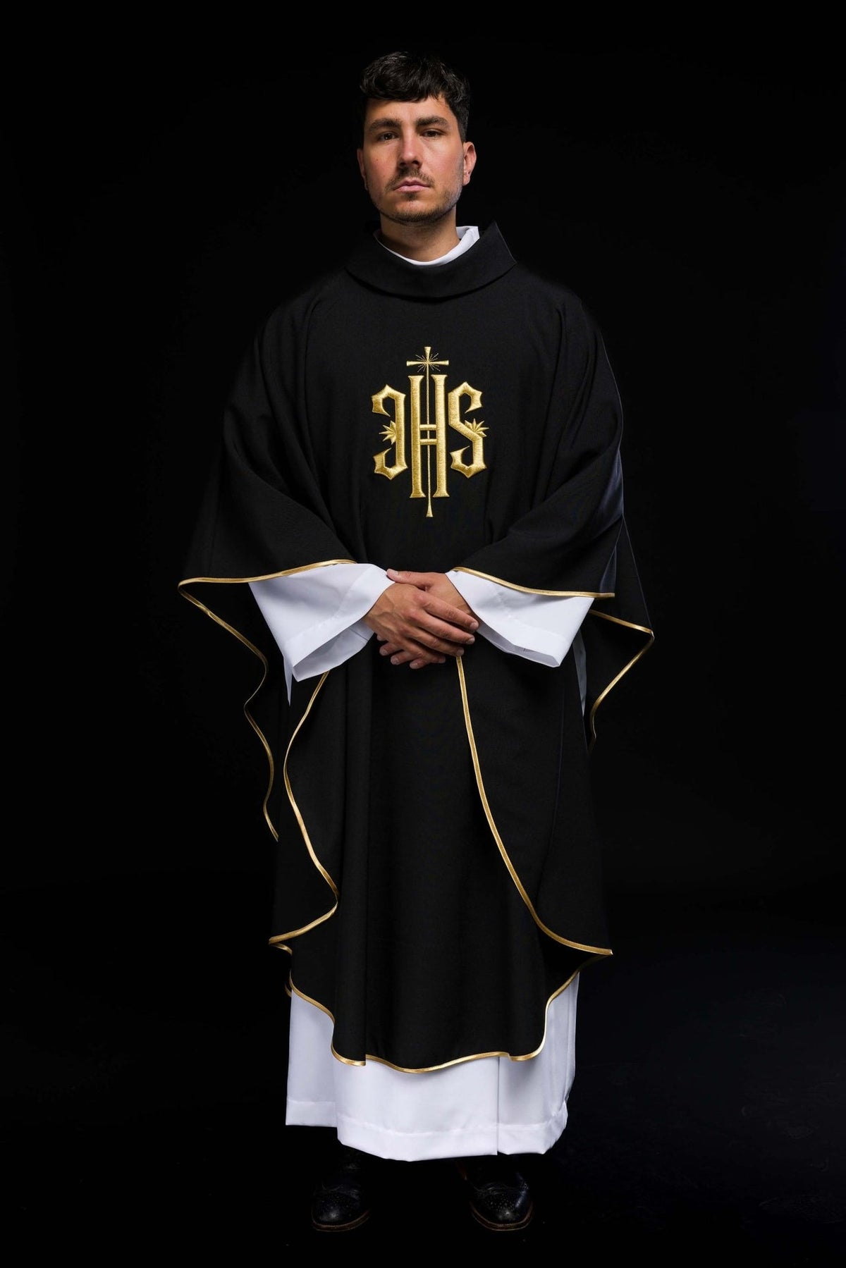 Black chasuble front view with gold IHS embroidery and flowing trim