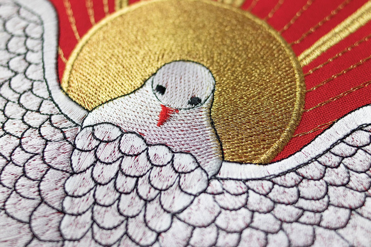 Red chasuble close-up of embroidered Holy Spirit wings and gold halo