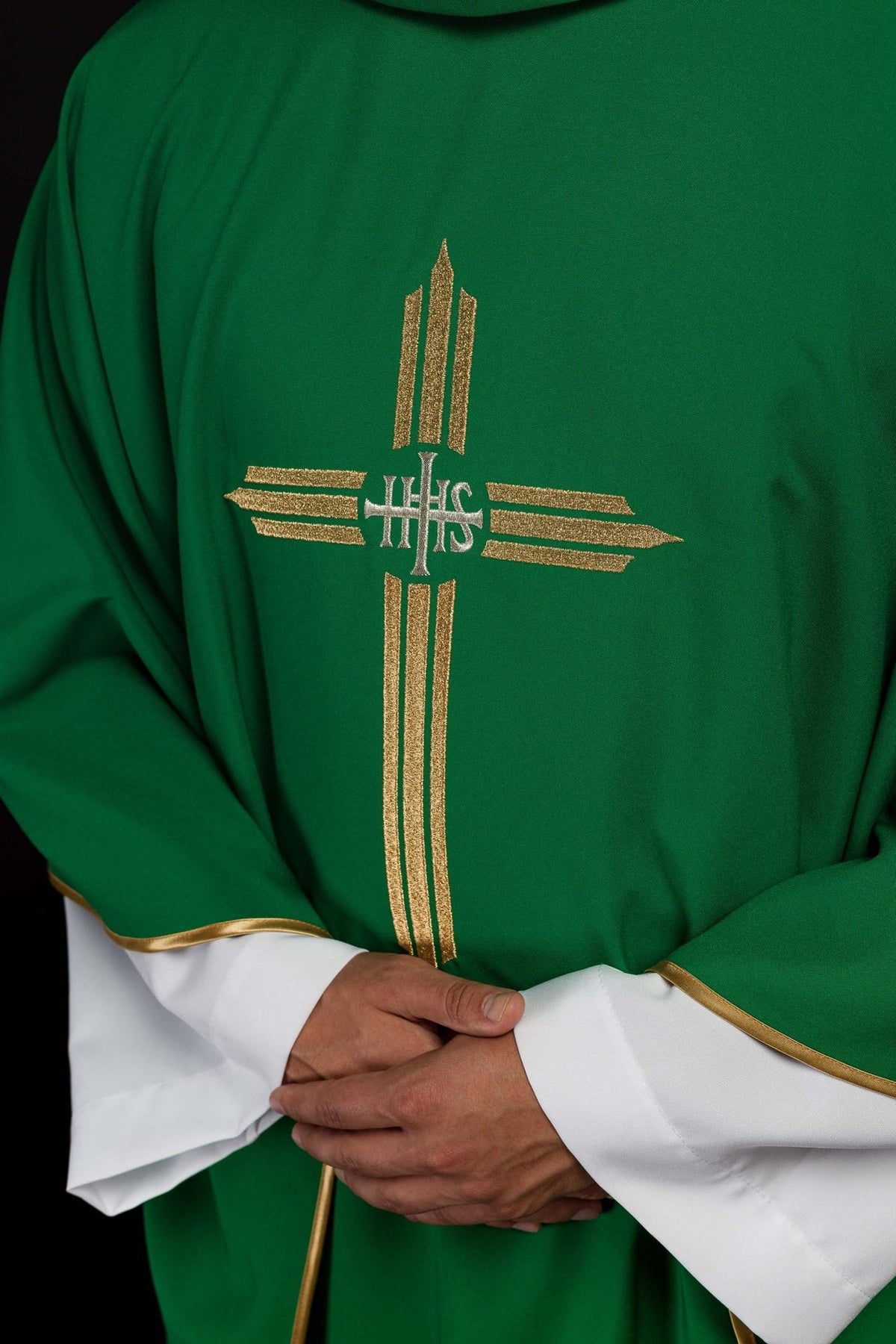 Green chasuble close-up showing silver IHS cross and gold embroidery