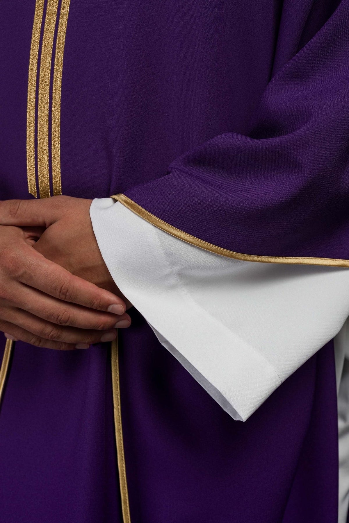 Purple chasuble close-up showing gold trim and white sleeve opening