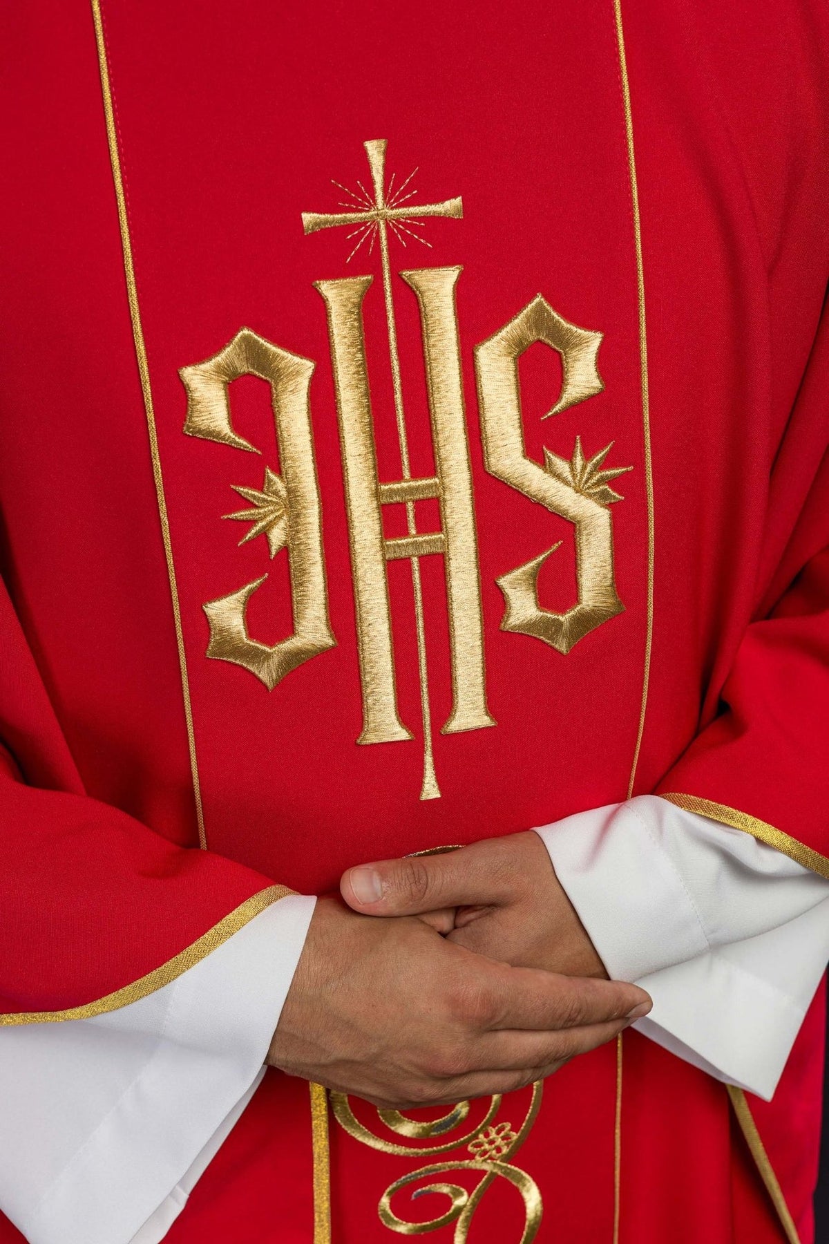 Red chasuble close-up showing gold embroidered IHS and trim