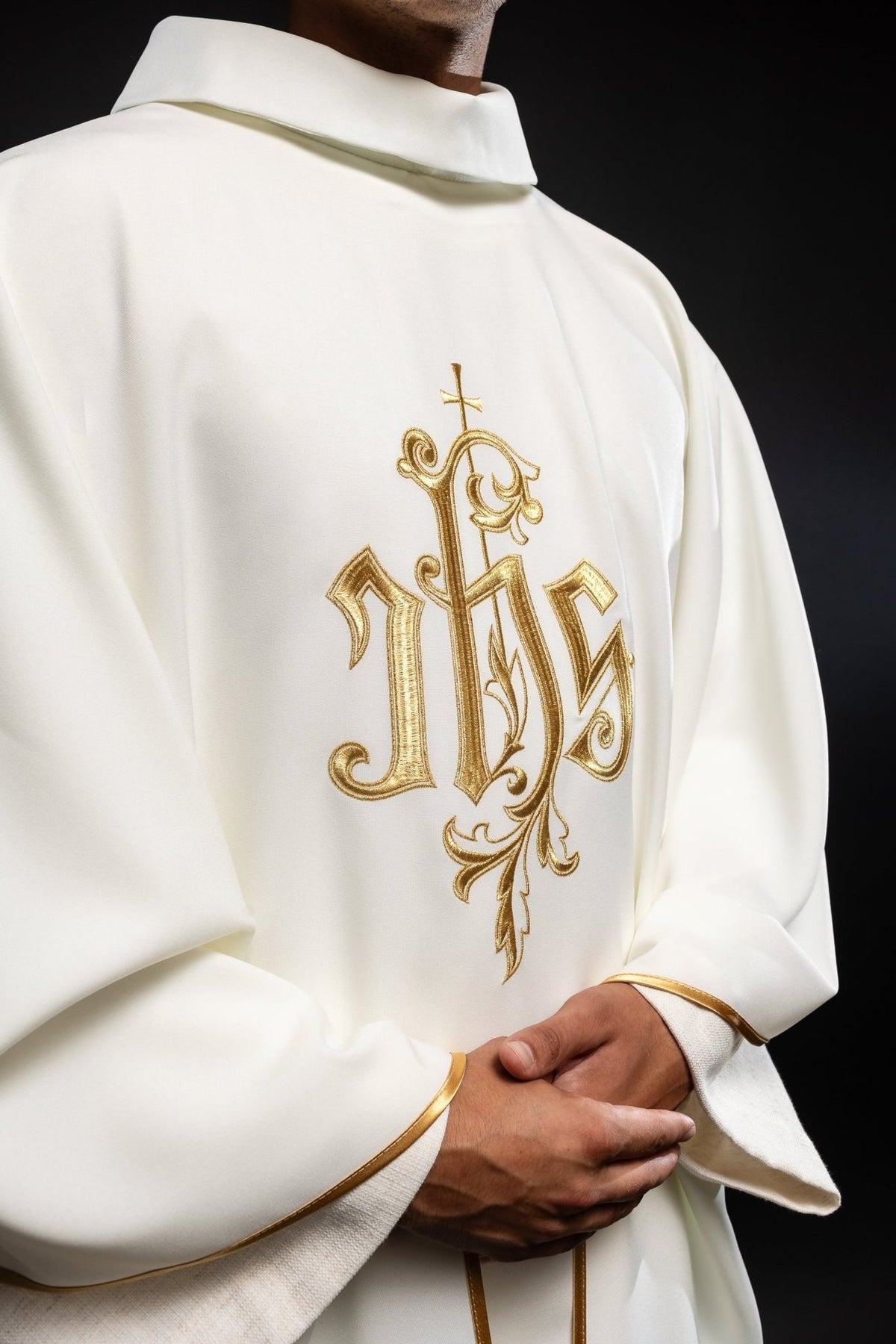 Cream chasuble close-up showing gold IHS embroidery, stand-up collar and sleeve trim